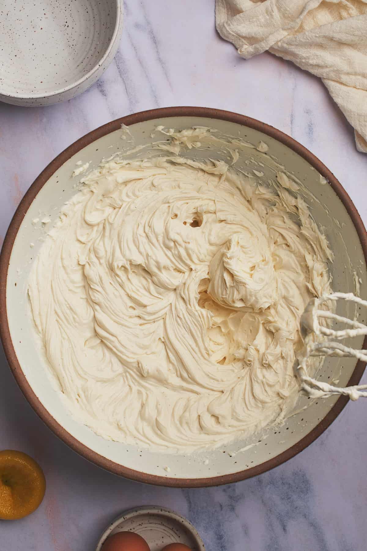 cream cheese cheesecake batter being mixed with a hand mixer. 