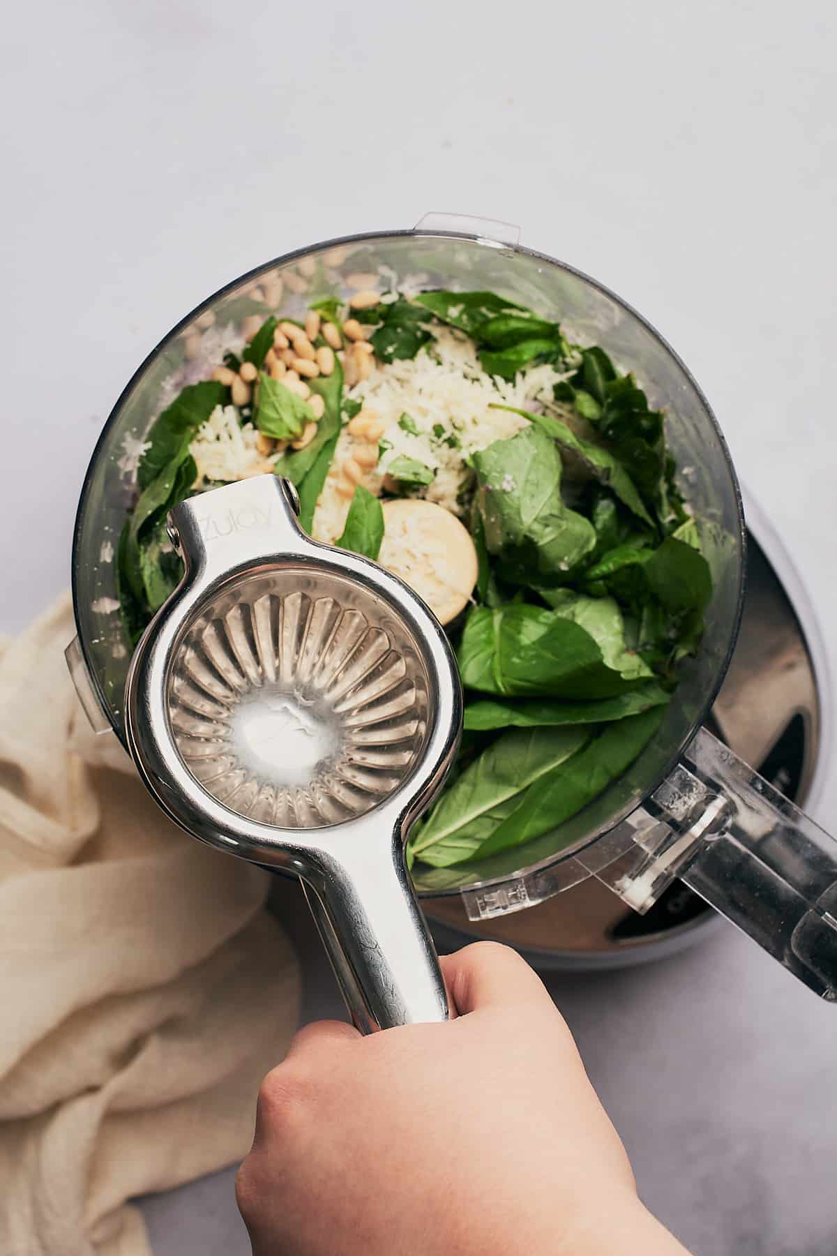 squeezing lemon juice with a citrus squeezer into a food processor.