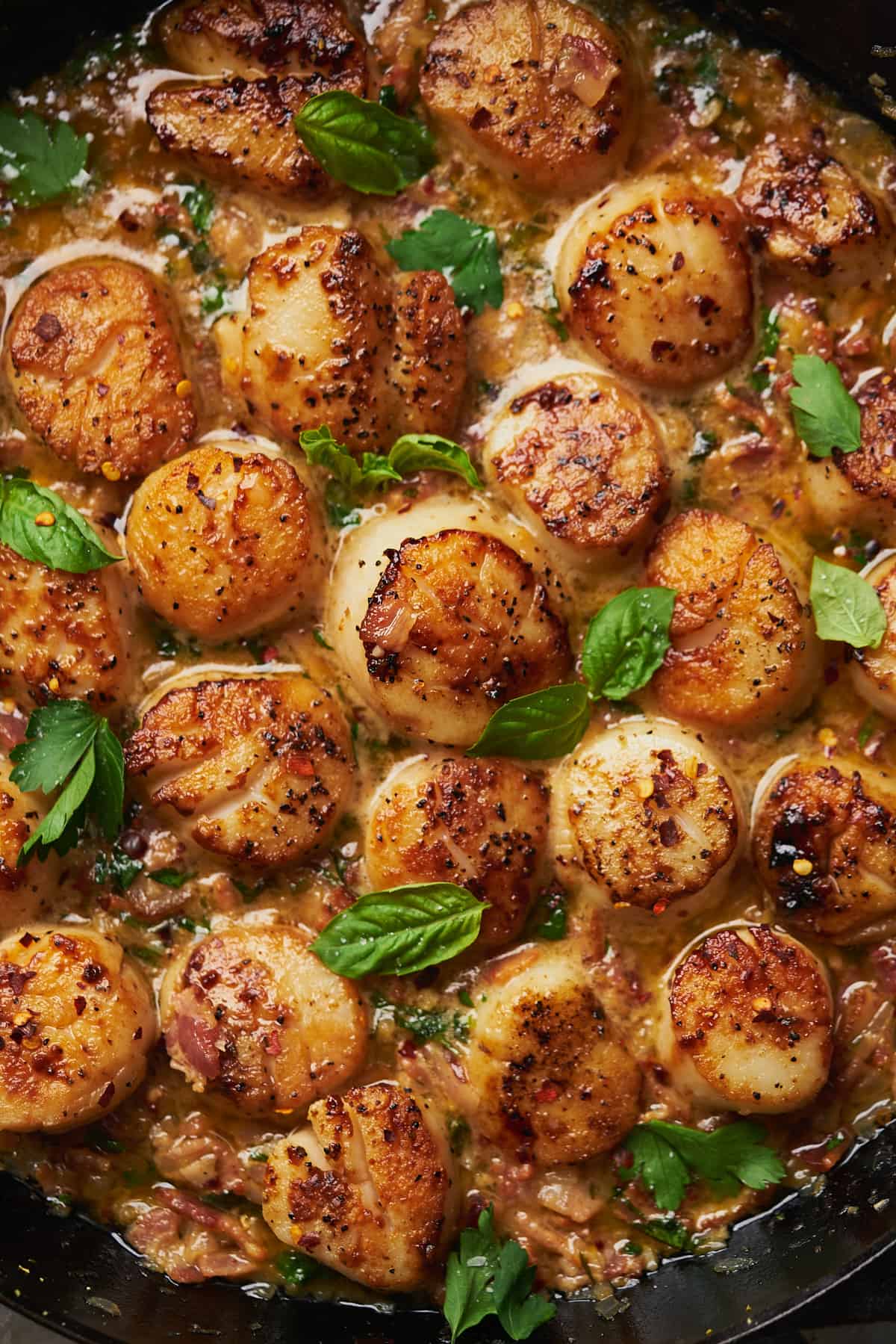 scallops seared in cast iron in a buttery pan sauce with basil. 