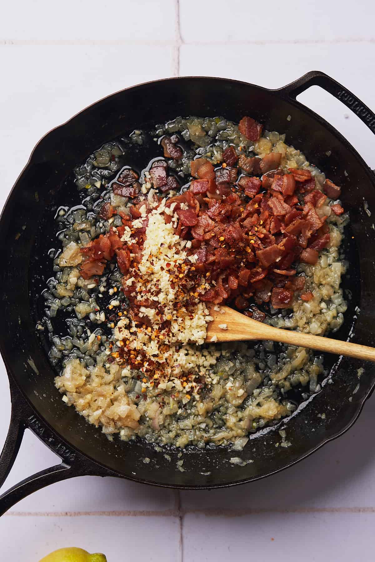 adding bacon and garlic to a pan with cooked shallots. 