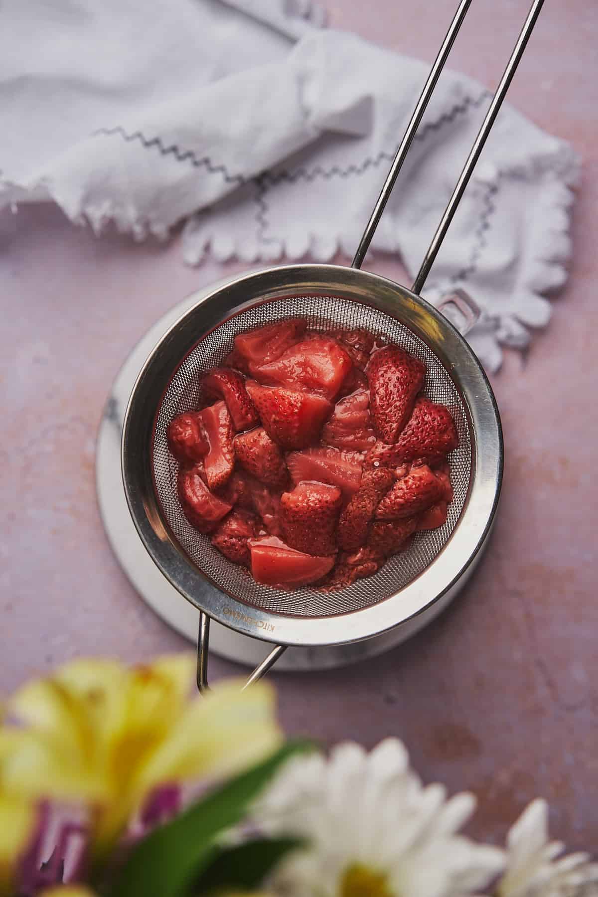 straining water away from cooked strawberries. 