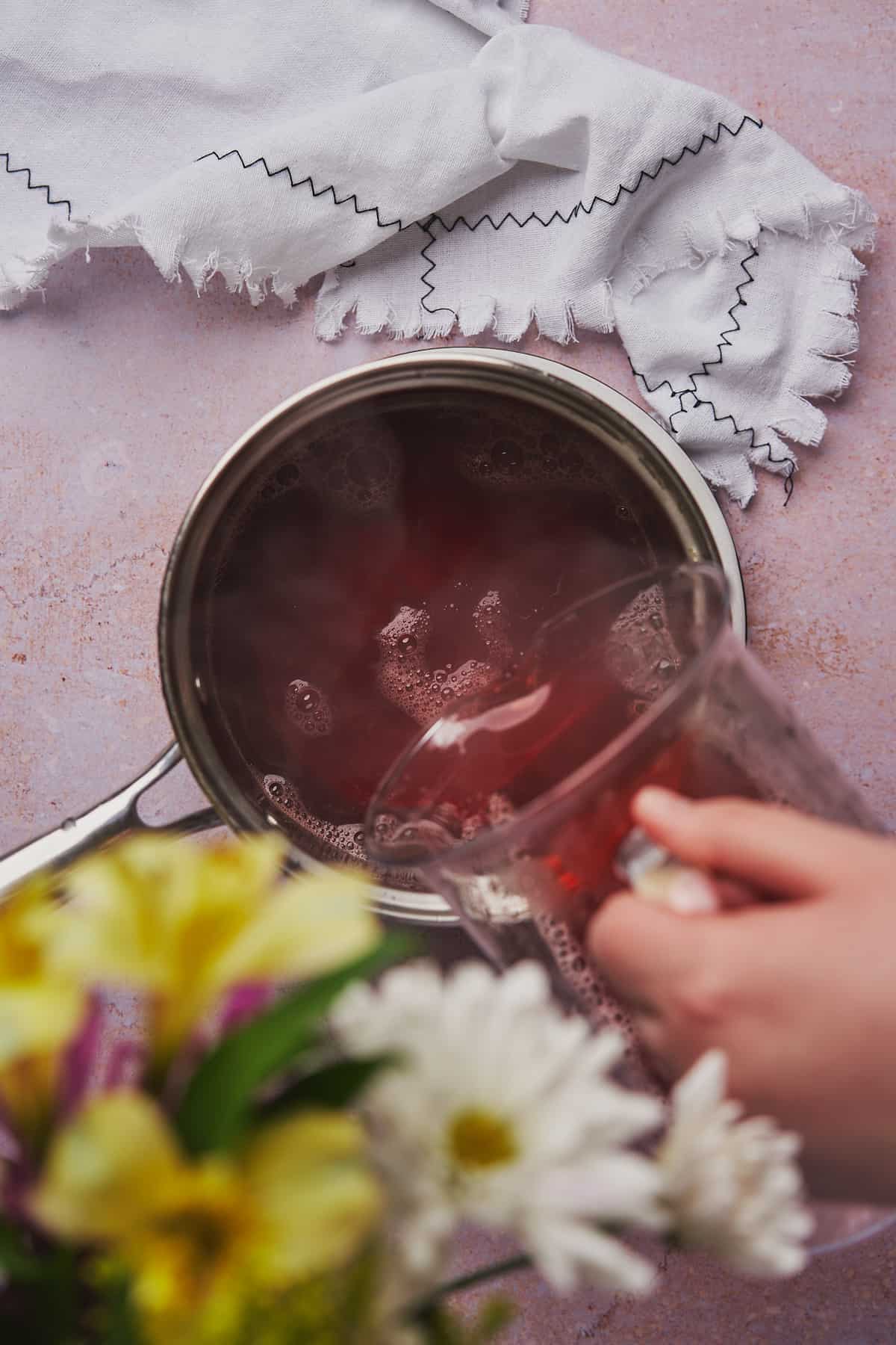 pouring strawberry syrup into a saucepan. 