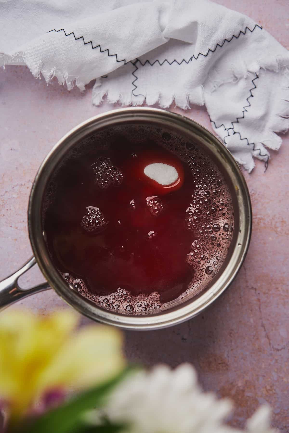 sweetener added to strawberry syrup in a saucepan. 