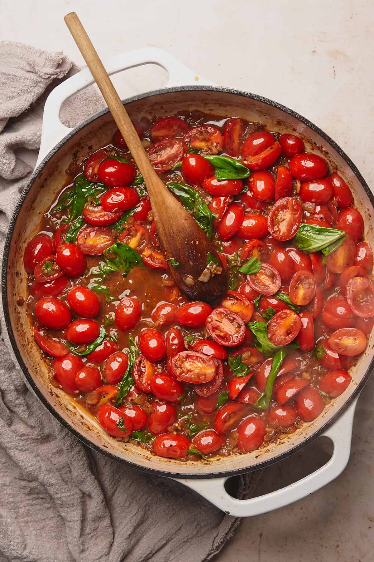 cherry tomato halves in a cast iron skillet with fresh basil, and some liquid in the pan. 