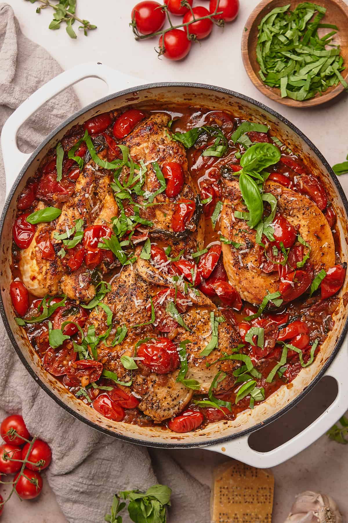 chicken pomodoro topped with fresh basil and parmesan cheese in an enameled cast iron skillet. 