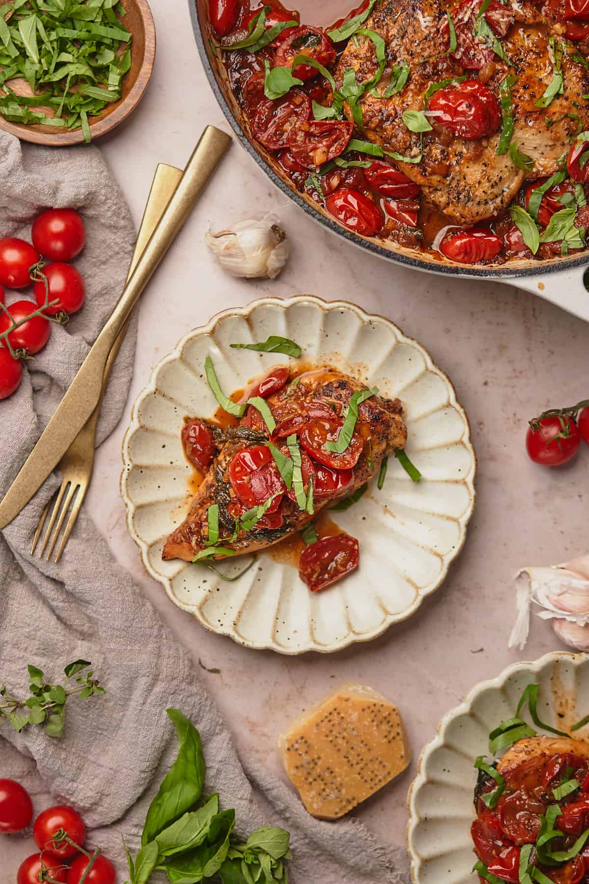 chicken pomodoro on a white ruffled plate, with a cast iron with the remaining chicken and tomatoes.