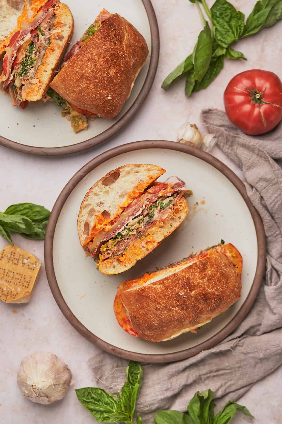 flat lay of a large spicy italian grinder sandwich, cut in half with the insider facing the camera so you can see the layers. 