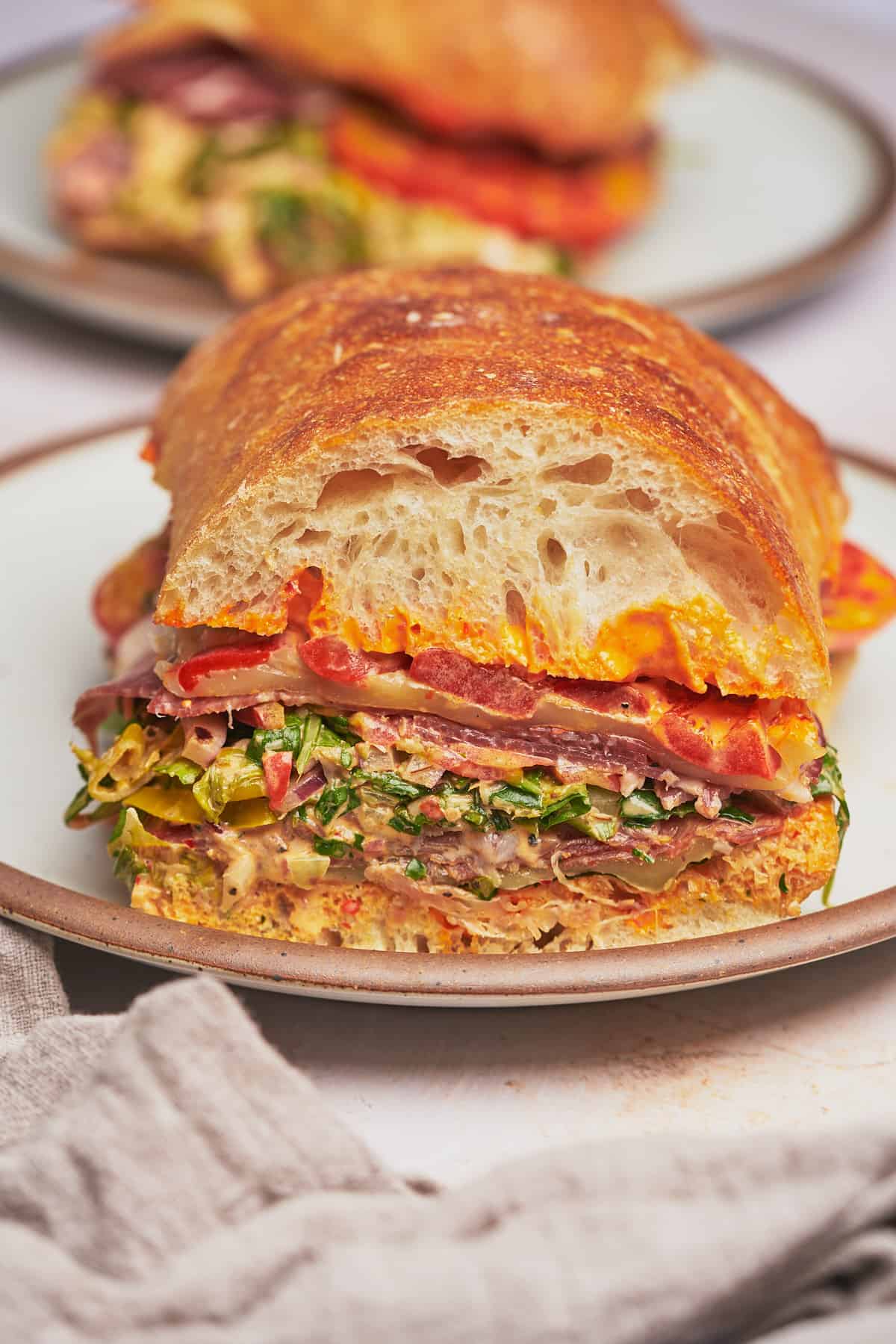Italian grinder sandwich standing tall on a large ceramic plate.
