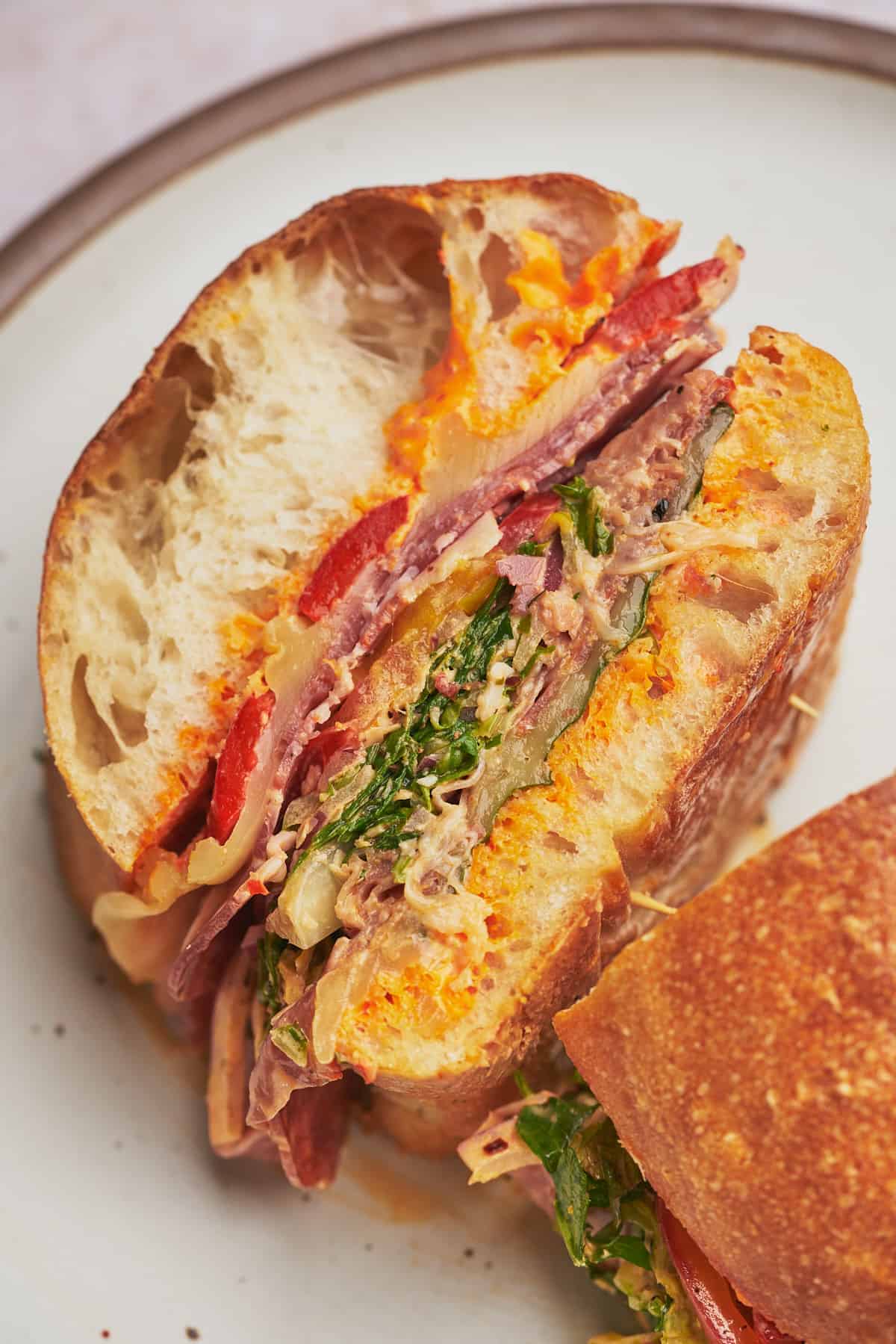 close up shot of a grinder sandwich laying face up and cut in half to show the delicious layers of the sandwich. 