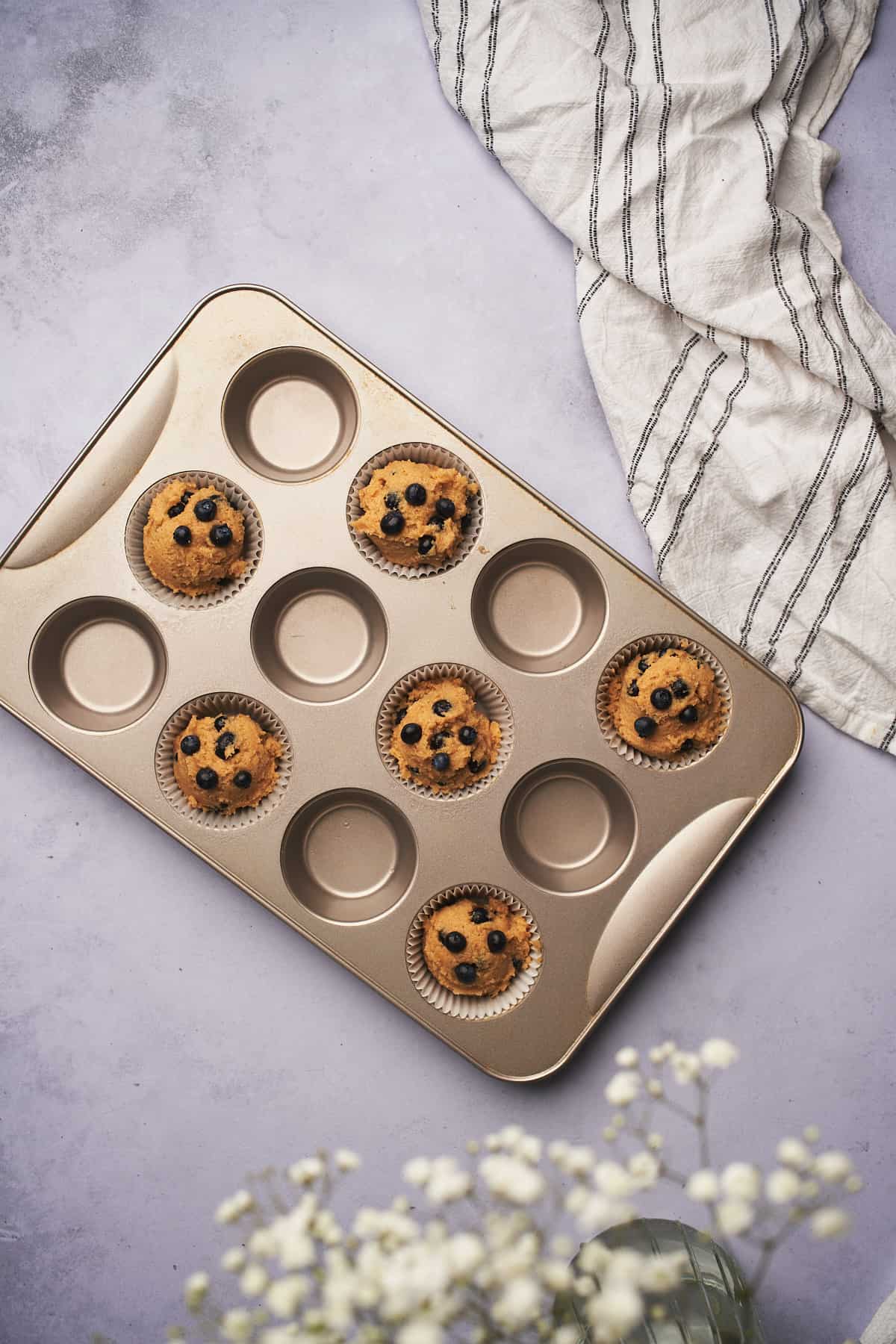 keto blueberry muffin batter in a half filled muffin tin. 