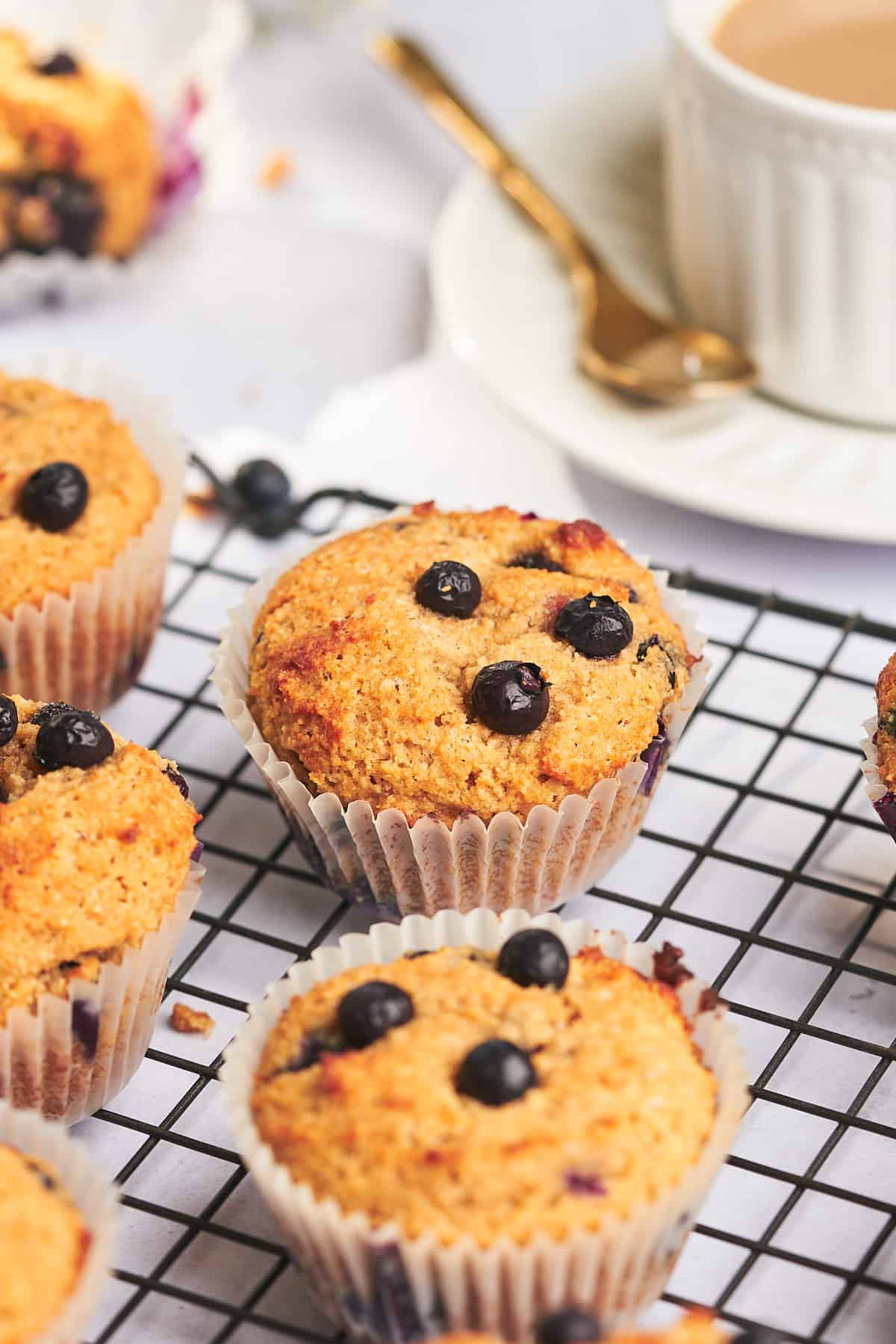 45 degree shot of a keto blueberry muffin on a black wire cooling rack. 