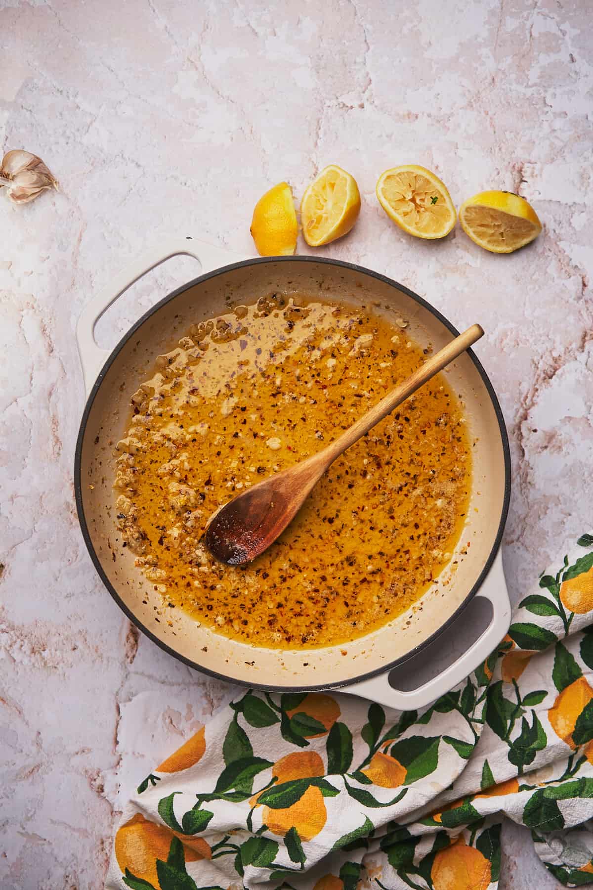 cooked garlic in butter and olive oil with lemons nearby in an enameled cast iron skillet. 