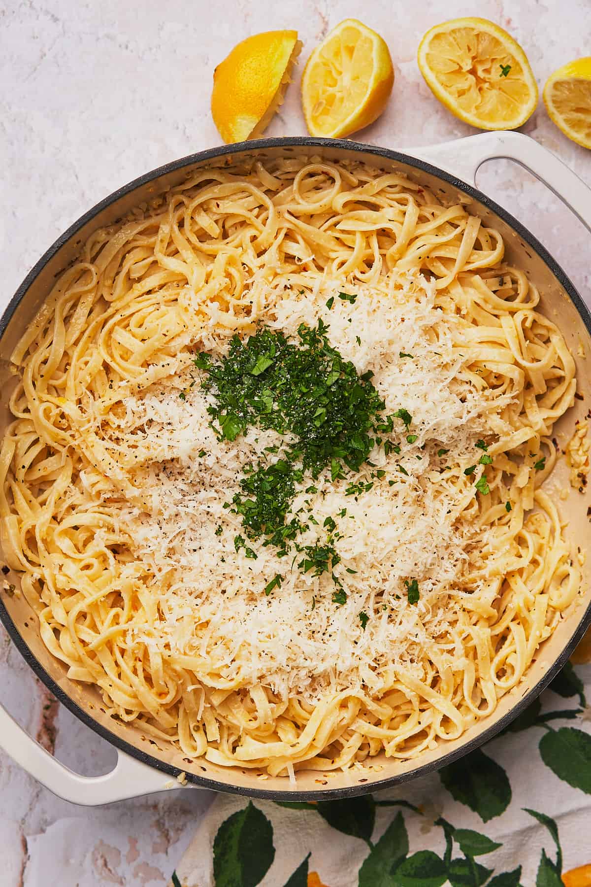 pasta in a cast iron skillet topped with freshly grate parmesan cheese and chopped parsley. 