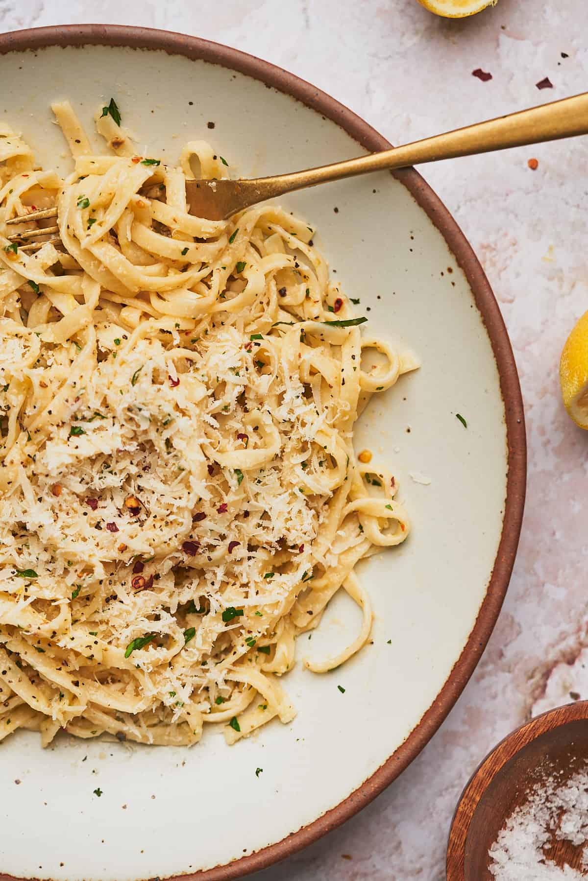 large bowl of lemon garlic pasta topped with fresh parmesan, and a juiced lemon nearby. 