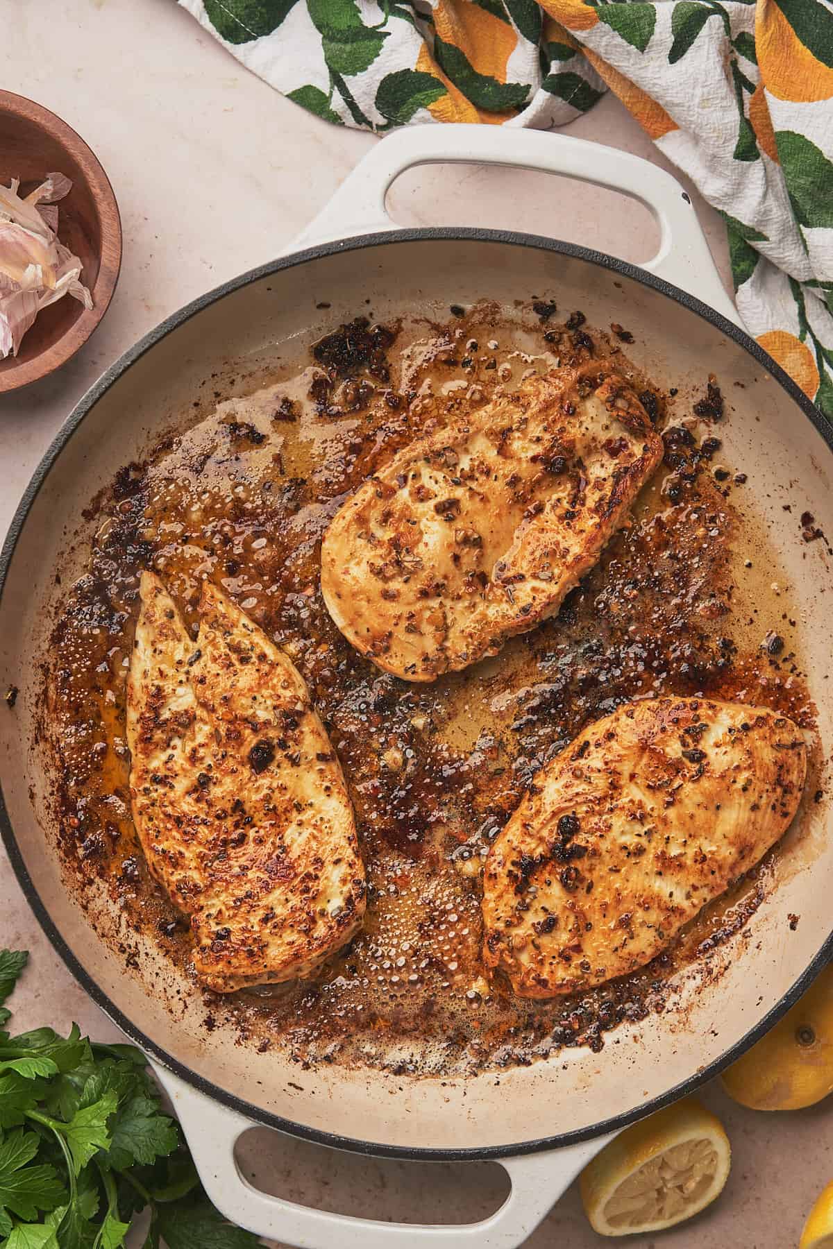 chicken breasts in a large skillet cooking in olive oil and butter. 