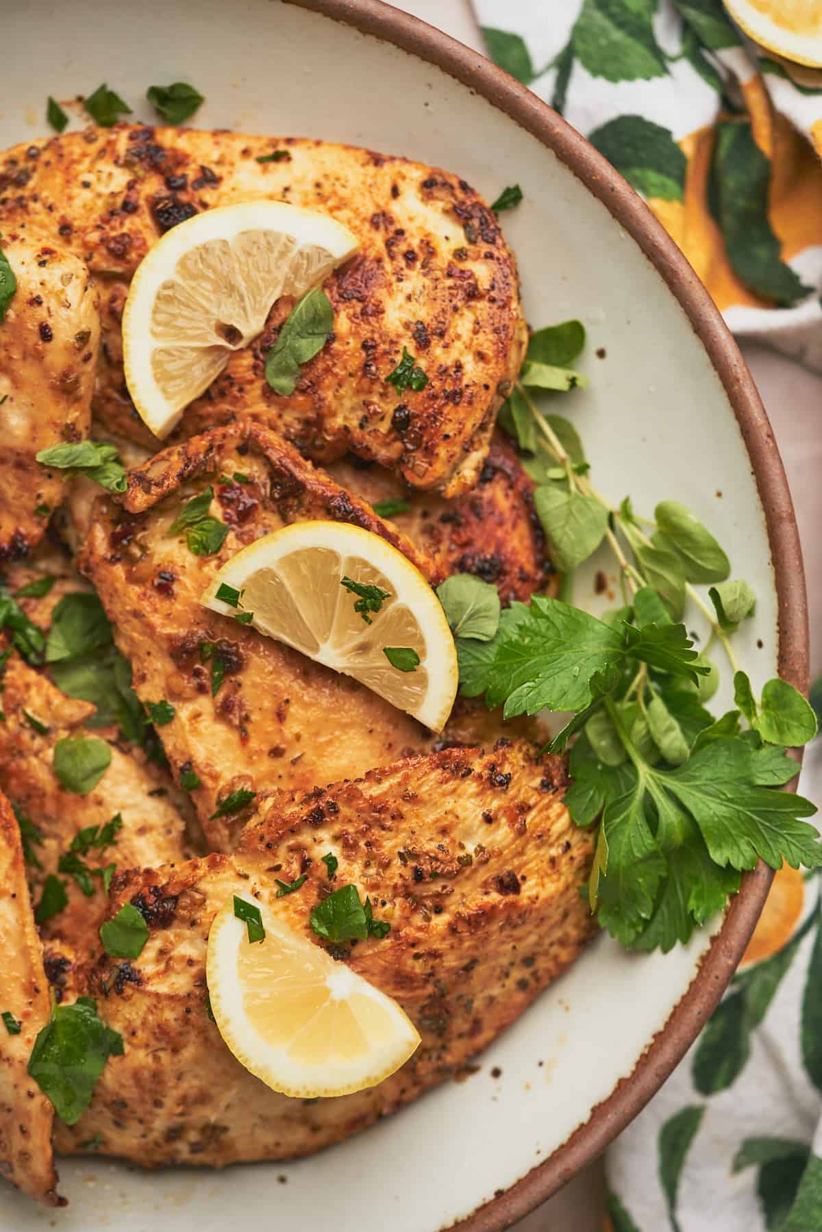 delicious lemon herb chicken breasts topped with fresh parsley, oregano, and lemon slices.