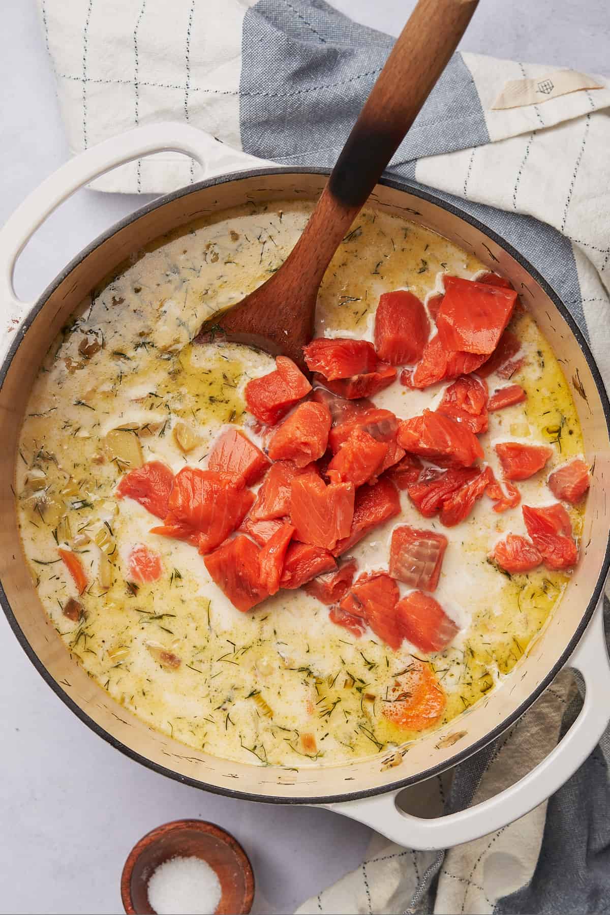 raw salmon pieces in a creamy broth in a dutch oven. 