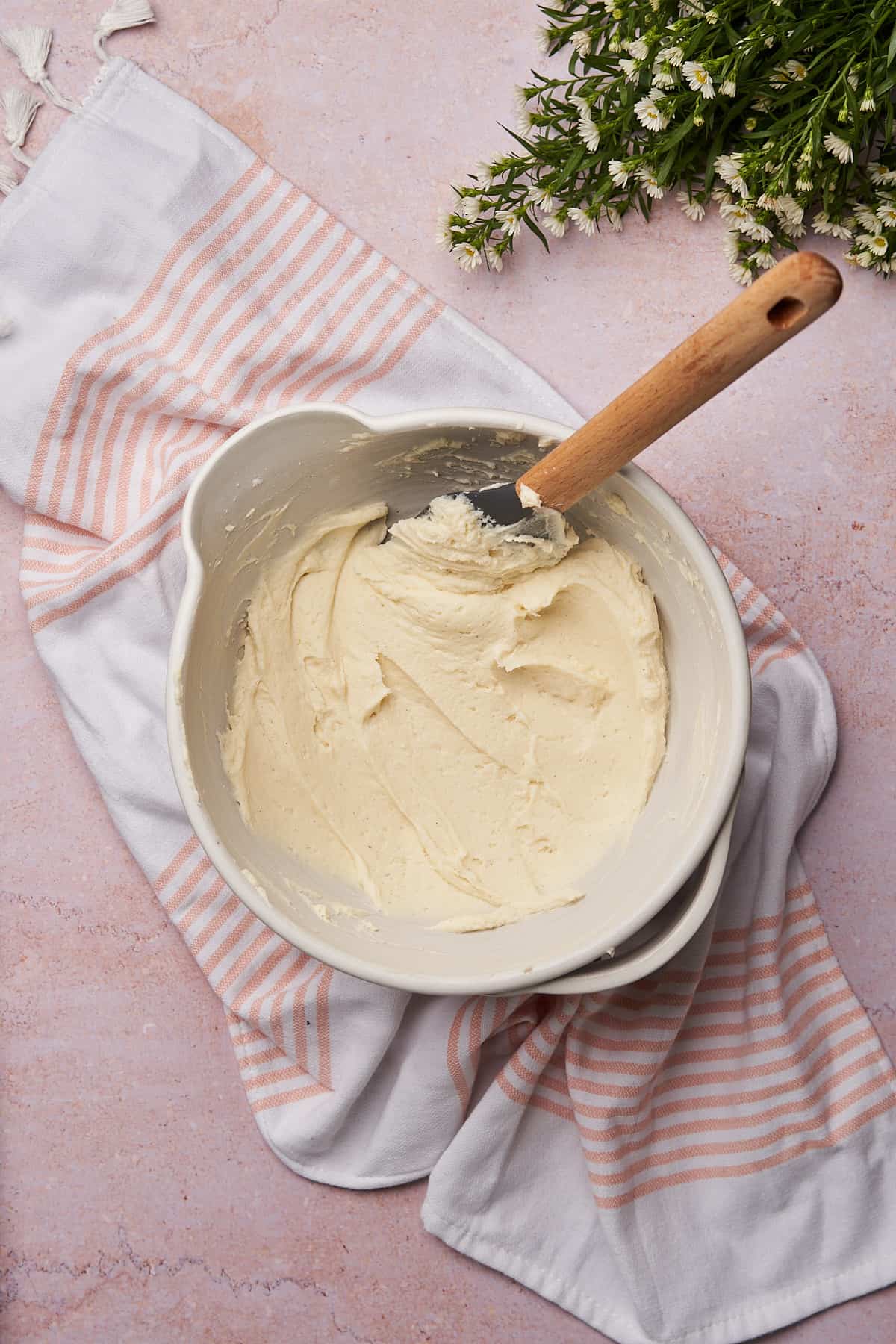 keto creamy cheese frosting in a white ceramic bowl with a rubber spatula inside. 