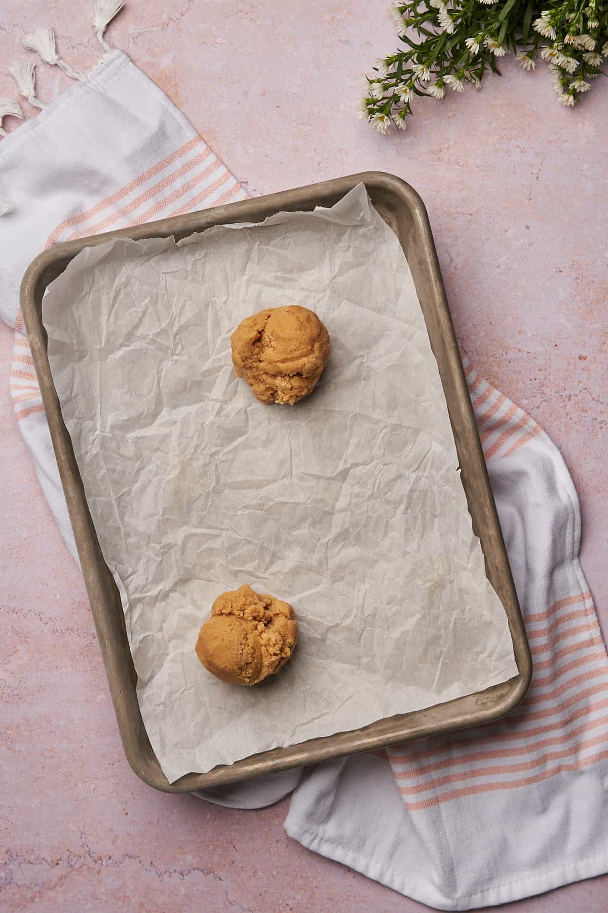 2 large balls of cookie dough on a parchment lined baking sheet. 