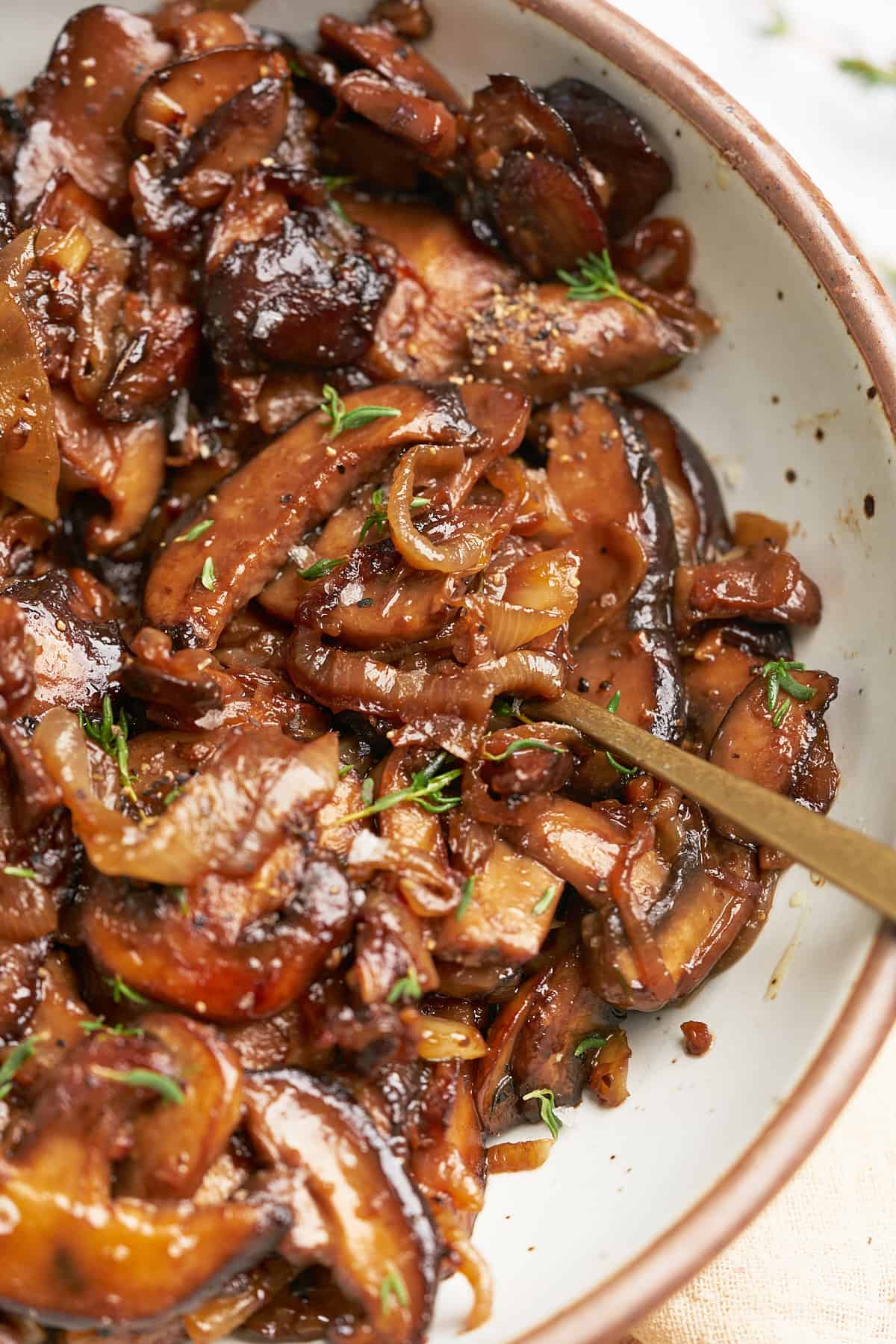 caramelized onions and mushrooms topped with fresh thyme in a bowl. 