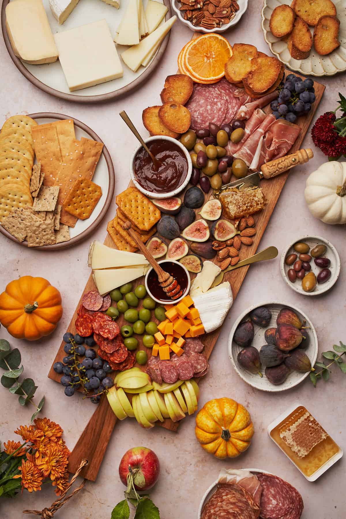 lovely fall charcuterie board with small orange and white pumpkins, fresh figs, nuts, cheeses, apples, and more. 