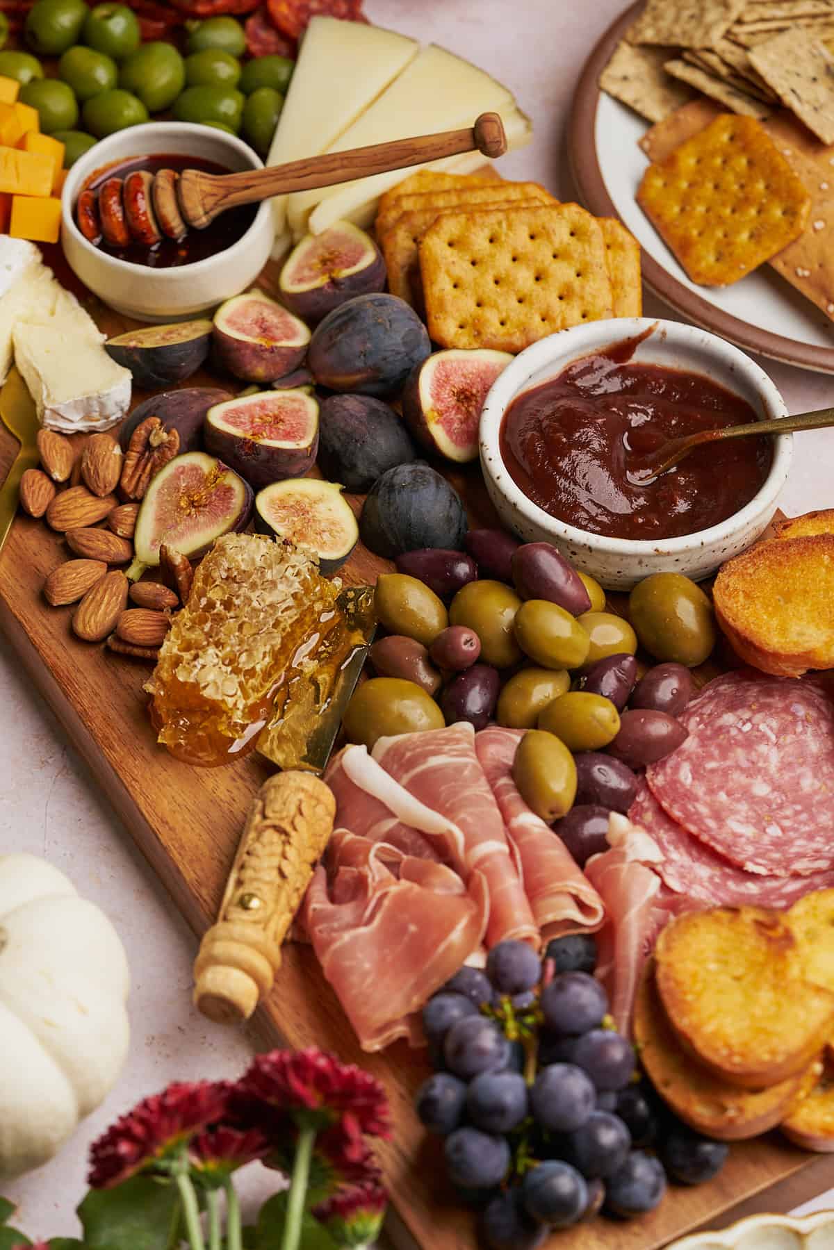 large fall charcuterie board with figs, honeycomb, proscuitto, olives, crackers, grapes, nuts, olives, and apple butter.