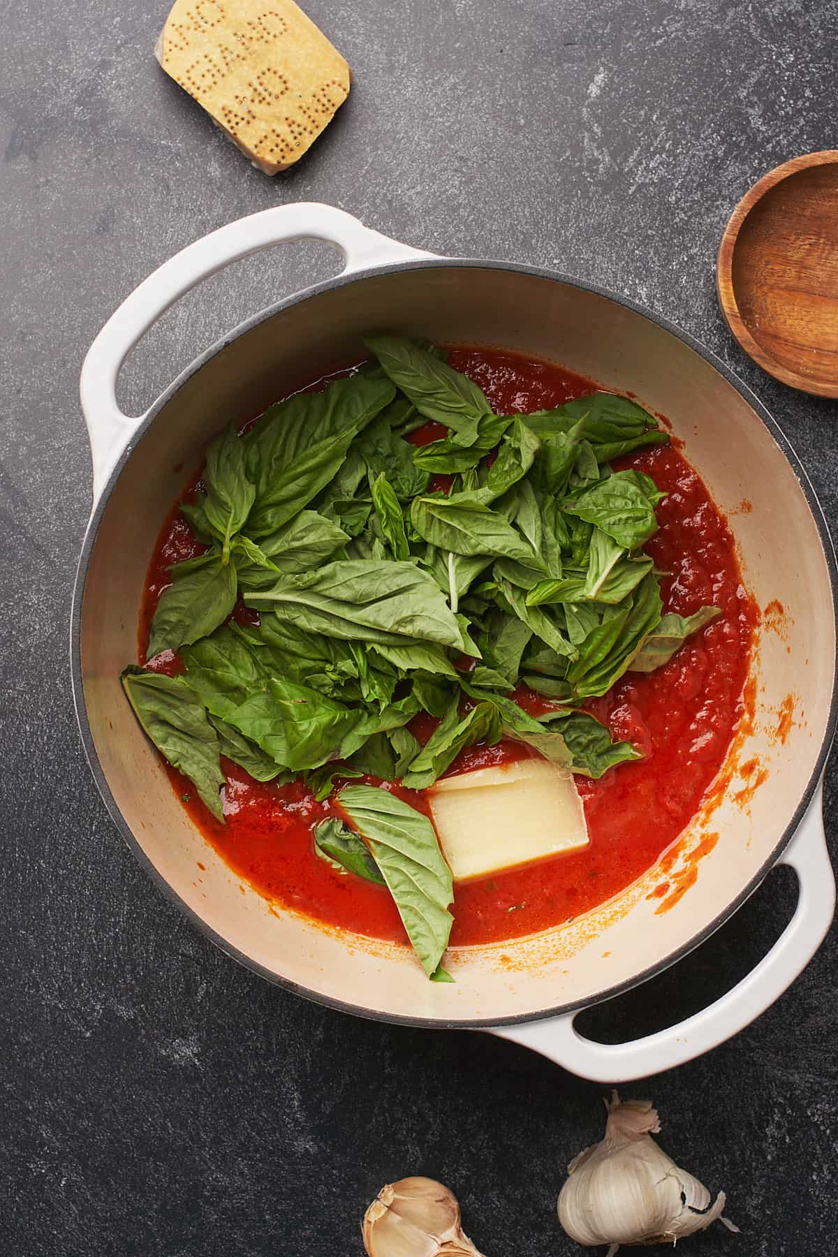 fresh basil, a parmesan cheese rind, and pasta sauce in a dutch oven. 