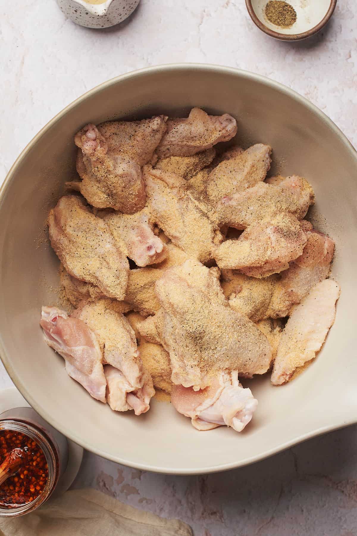 raw chicken wings coated in seasonings in a large bowl. 