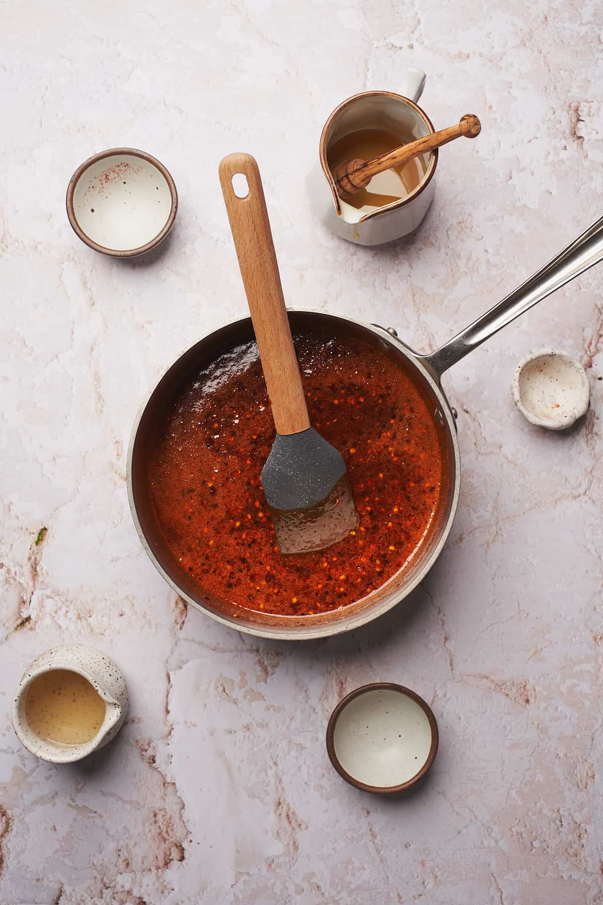 hot honey mixture with seasonings in a saucepan, with honey turning a nice red color. 