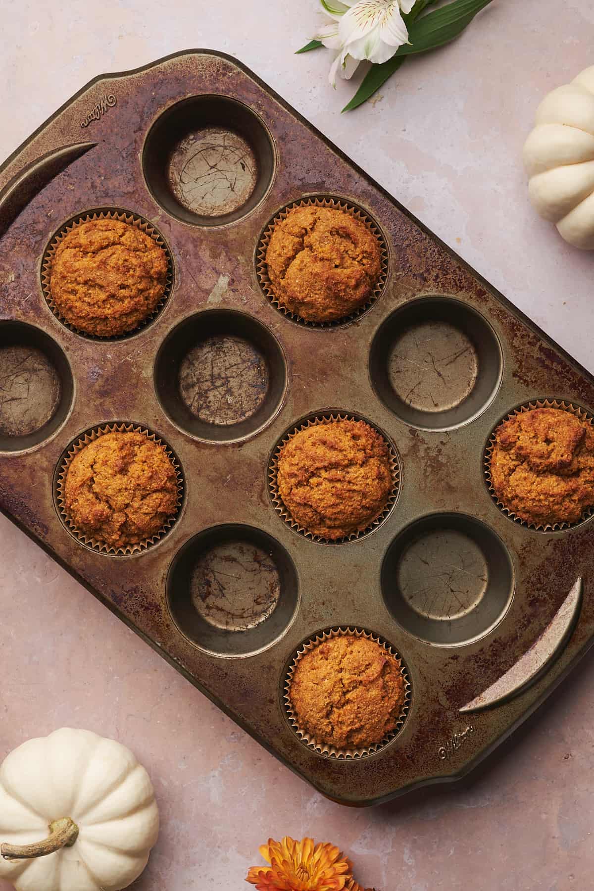 baked pumpkin muffins in a half full muffin tin.