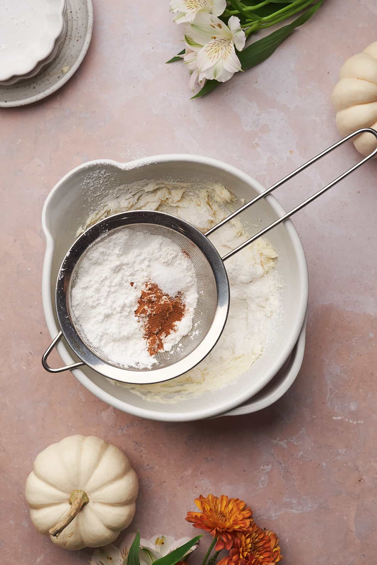 sifting in powdered sweetener, cinnamon, and salt into a mixing bowl with cream cheese. 