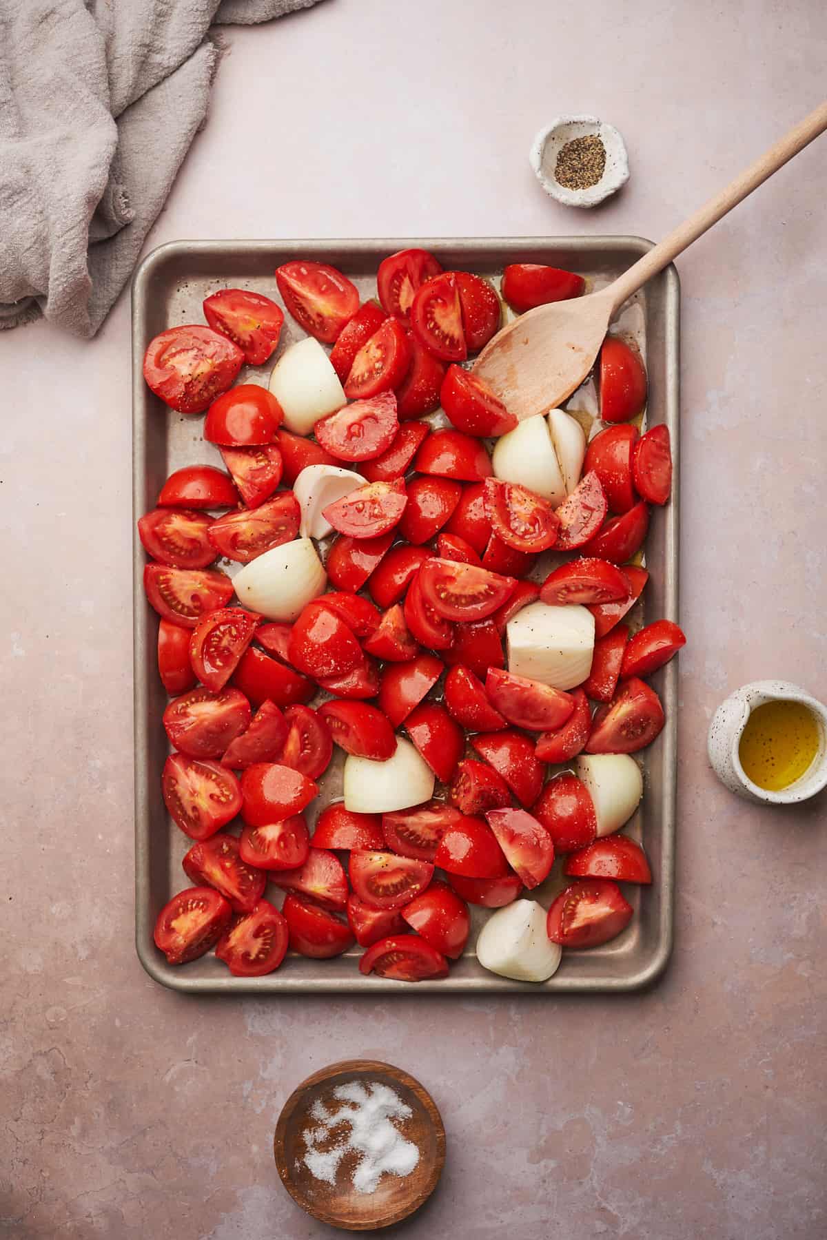 tomatoes and onions on a baking sheet with a wooden spoon. 
