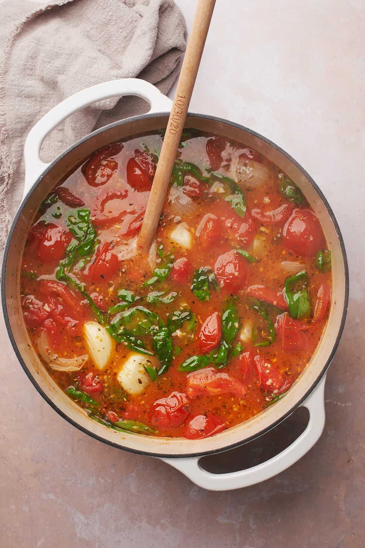 tomato soup in a dutch oven with onions, and wilted basil.