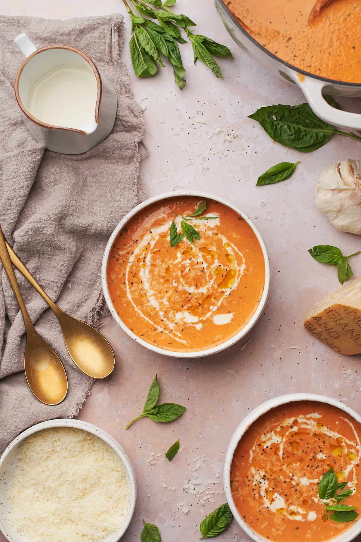 two bowls of keto tomato soup topped with cream, fresh basil, and olive oil. 