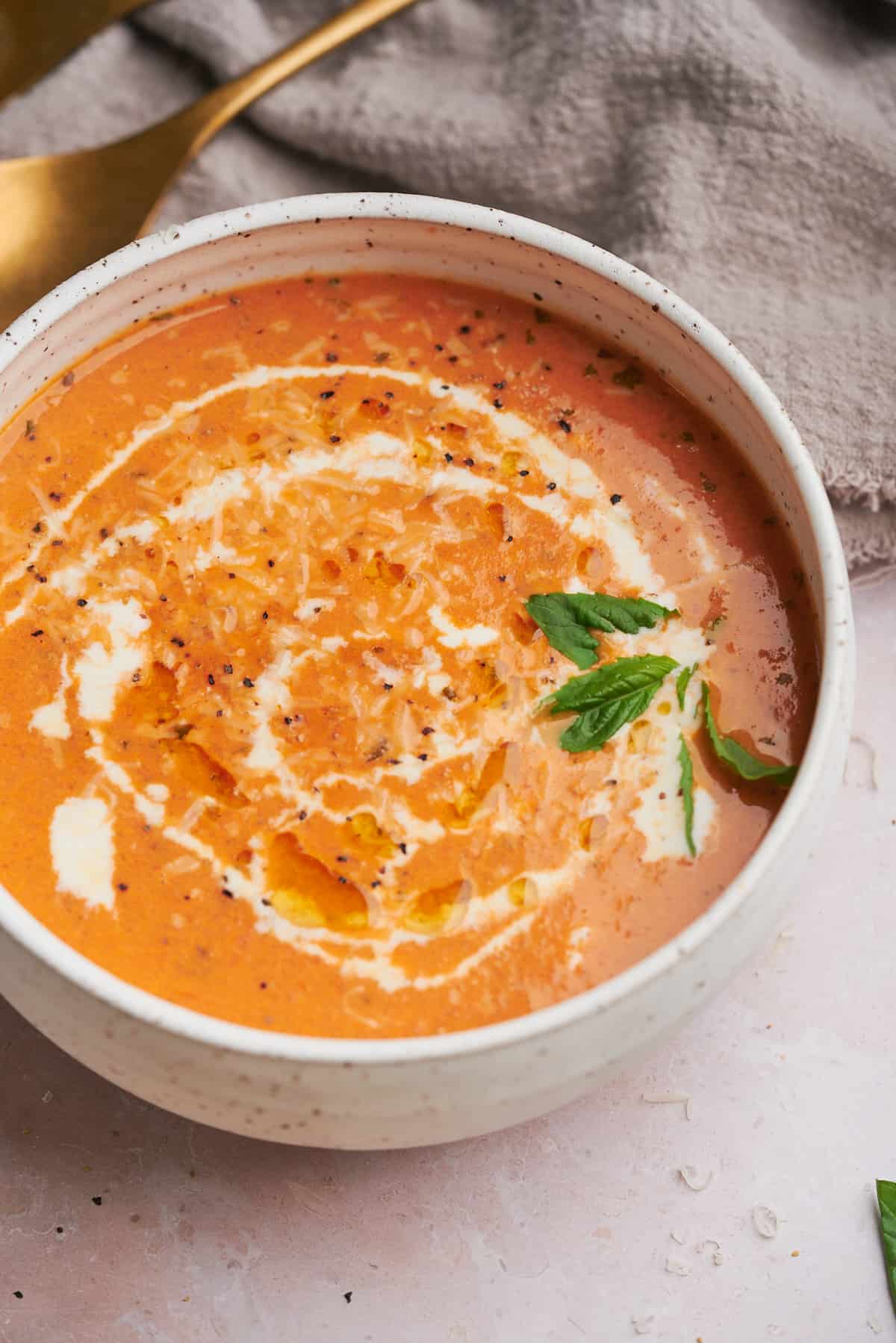 bowl of creamy tomato soup with fresh cream, olive oil and and basil. 