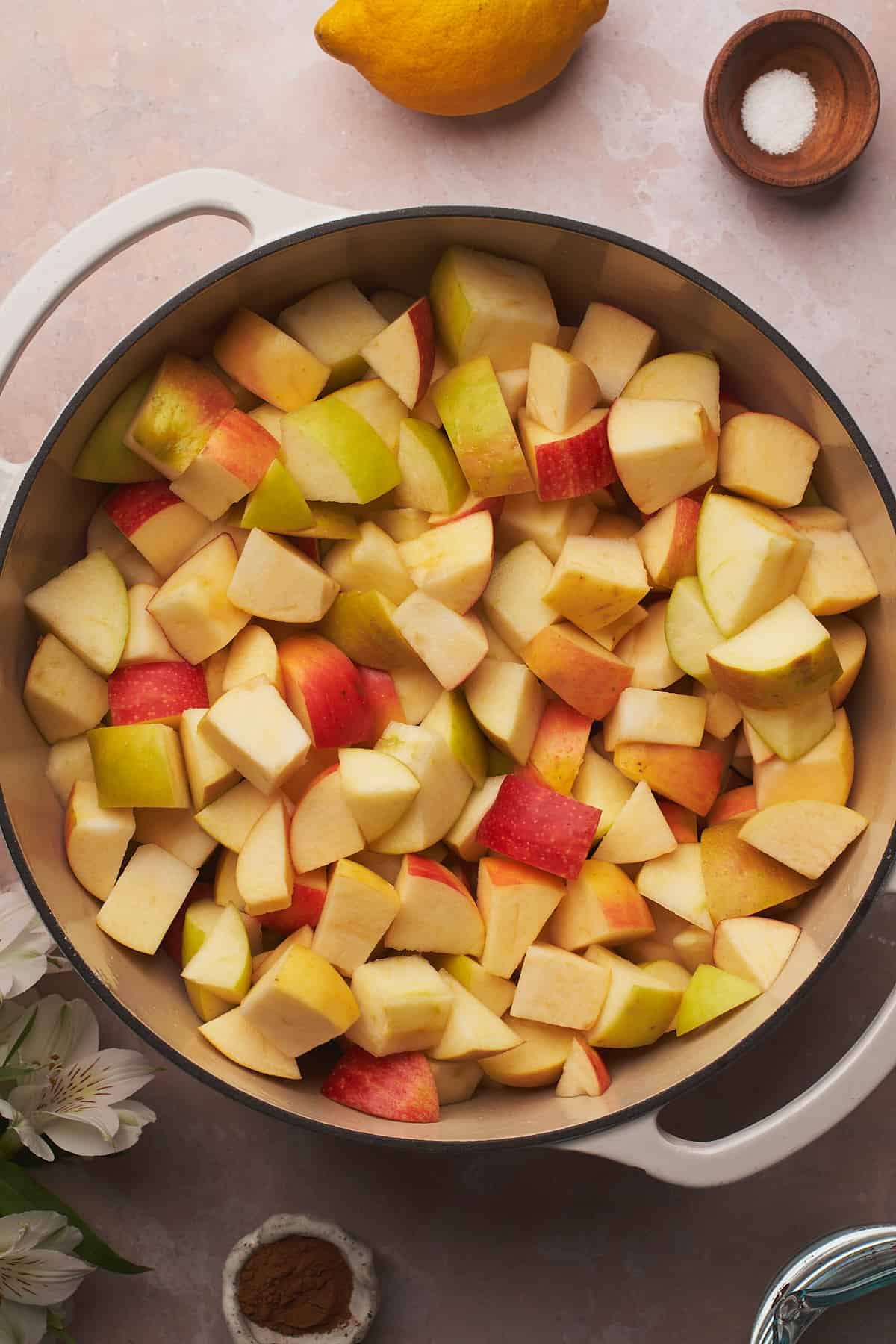 apples in a large pot with a few white flowers and apples surrounding the pot. 