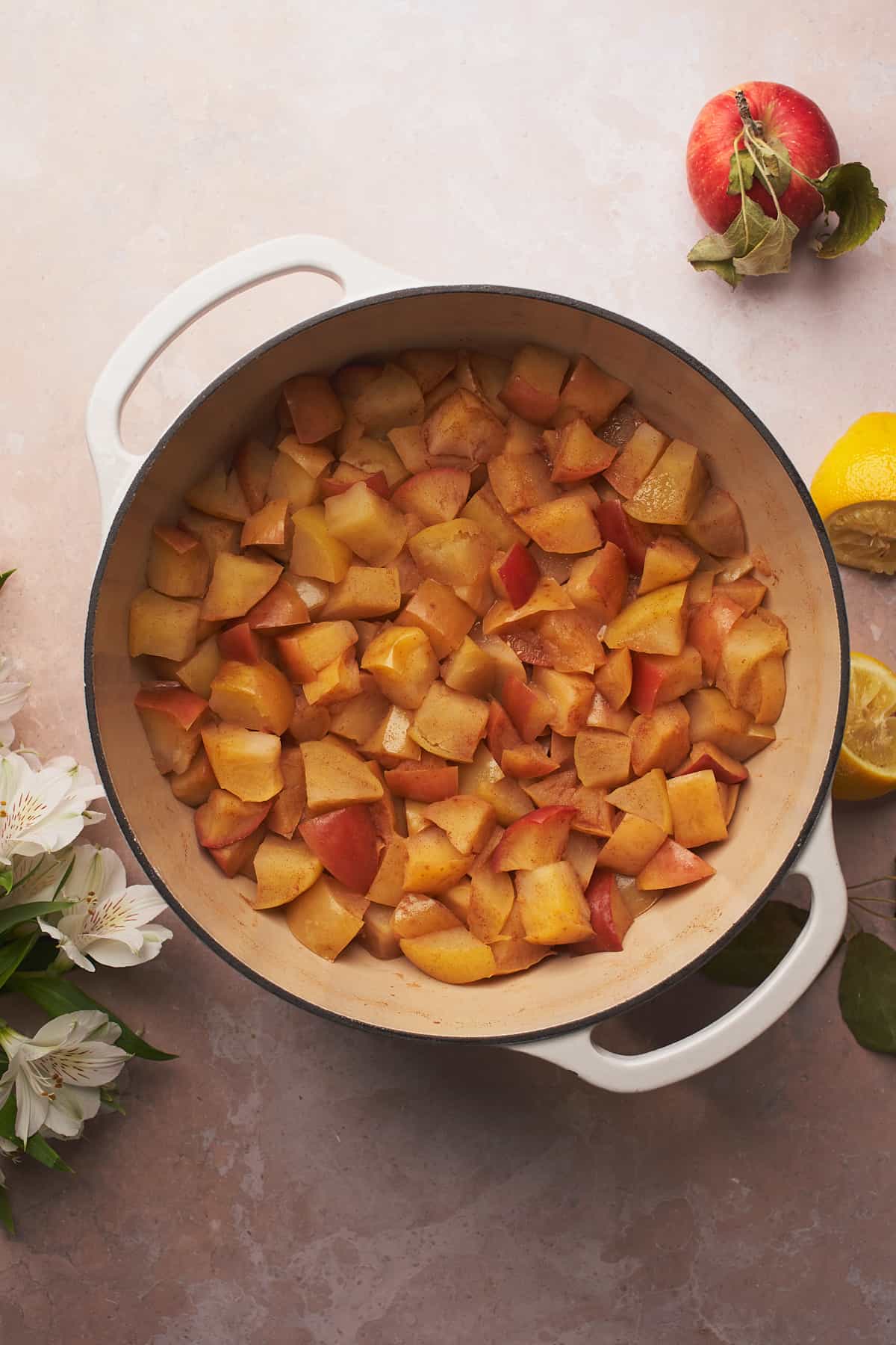 softened apples in a dutcb oven surrounded by white flowers and spent lemons.