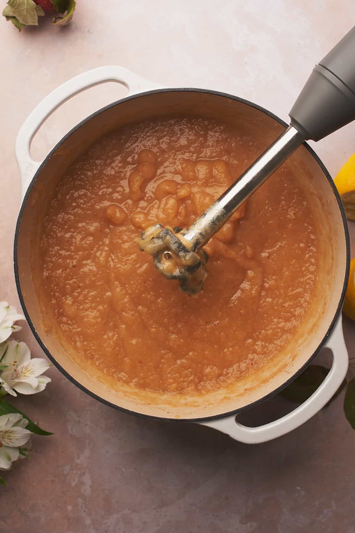 immersion blender in an enameled dutch oven pureeing applesauce. 