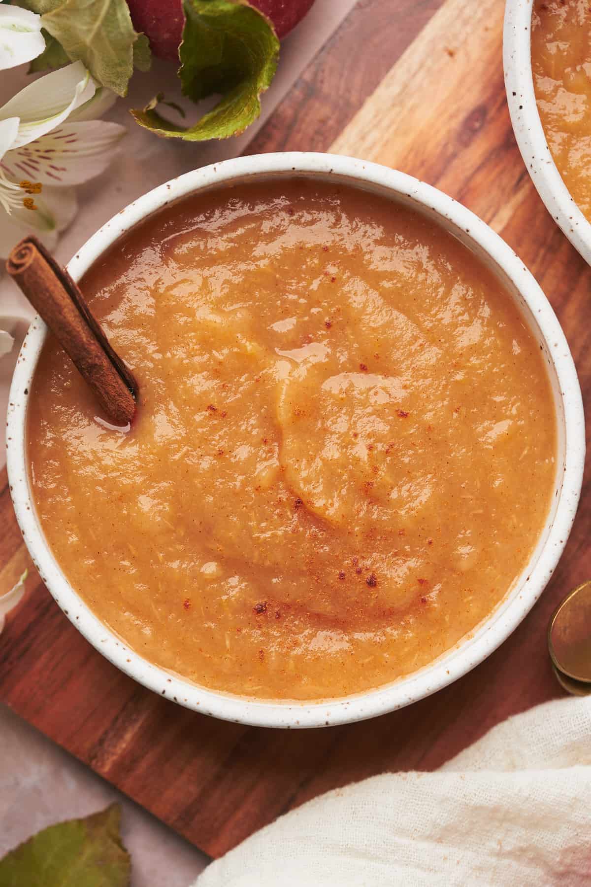 bowl of applesauce with a cinnamon stick and fresh cinnamon on top. 