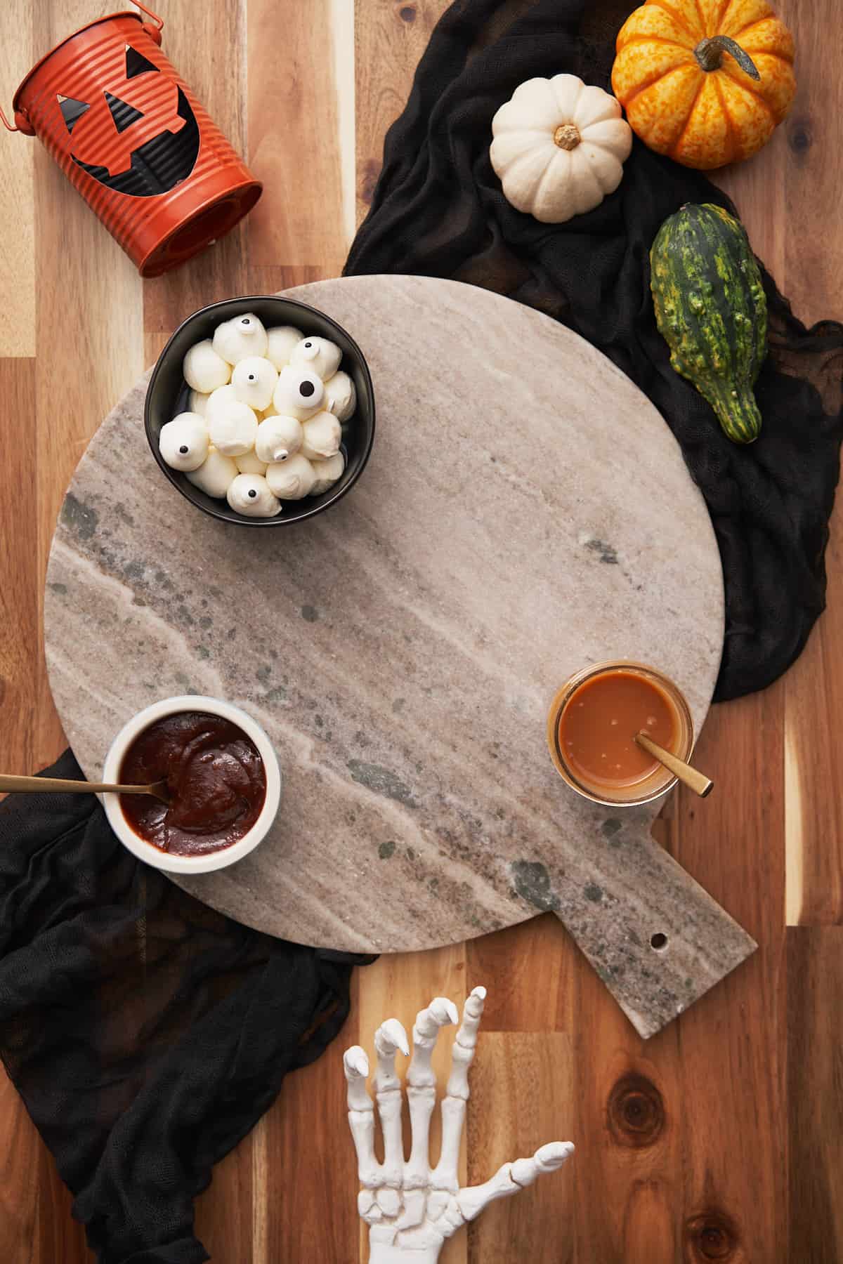 marble charcuterie board with caramel sauce, apple butter, and mozzarella balls with candy eyeballs. 