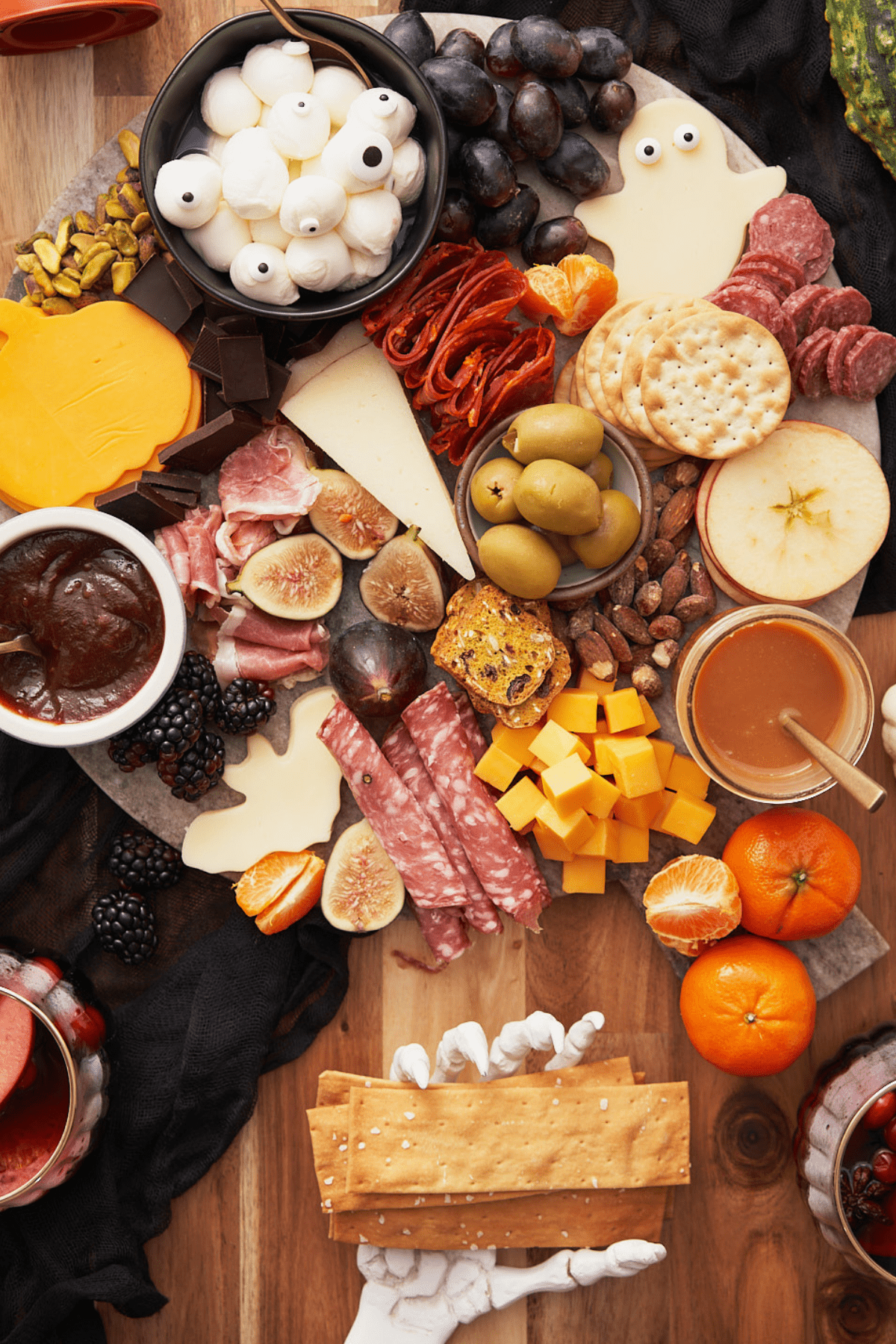 halloween charcuterie board with cute spooky cutouts, fruit, meats, and a skeleton hand. 