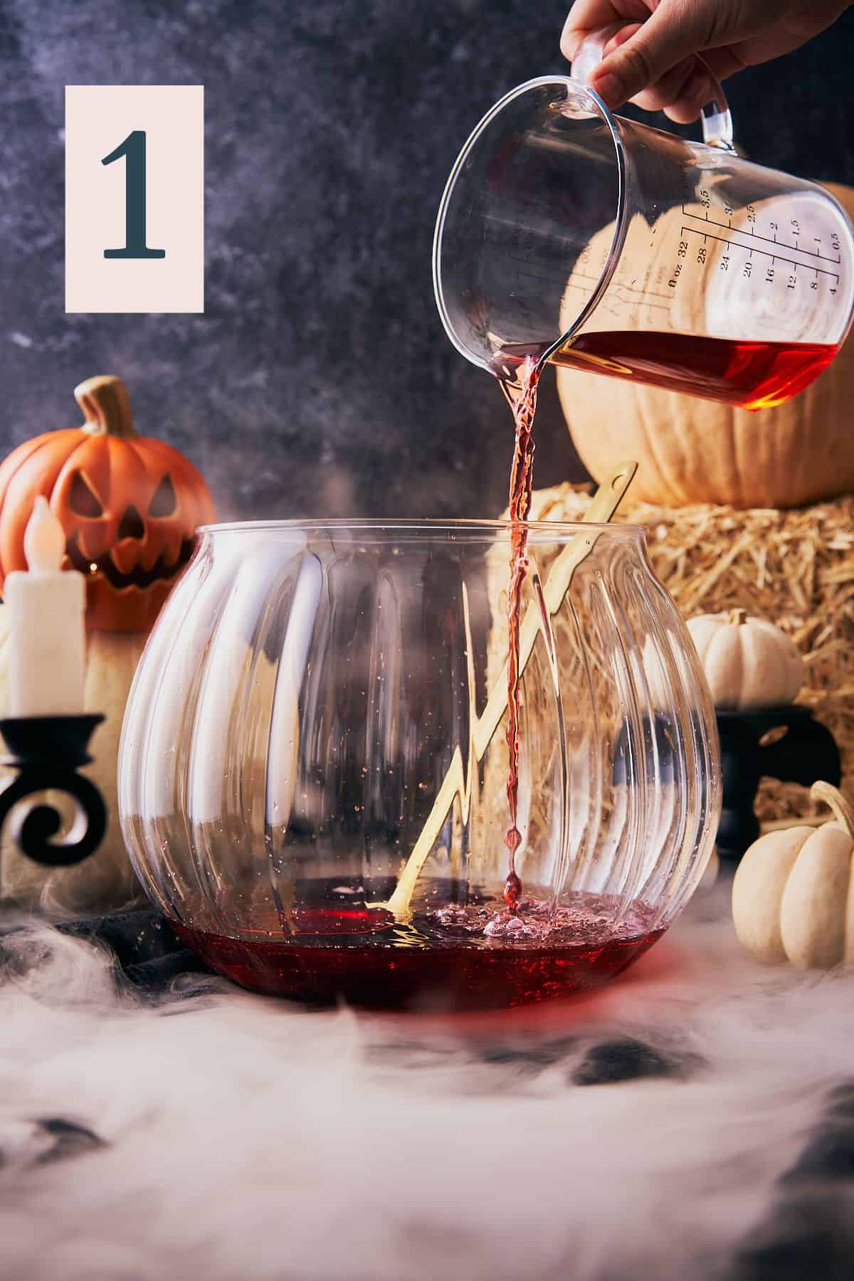 hand pouring cranberry juice into a large punch bowl with a spooky scene in the background and number 1 in the upper left hand corner.