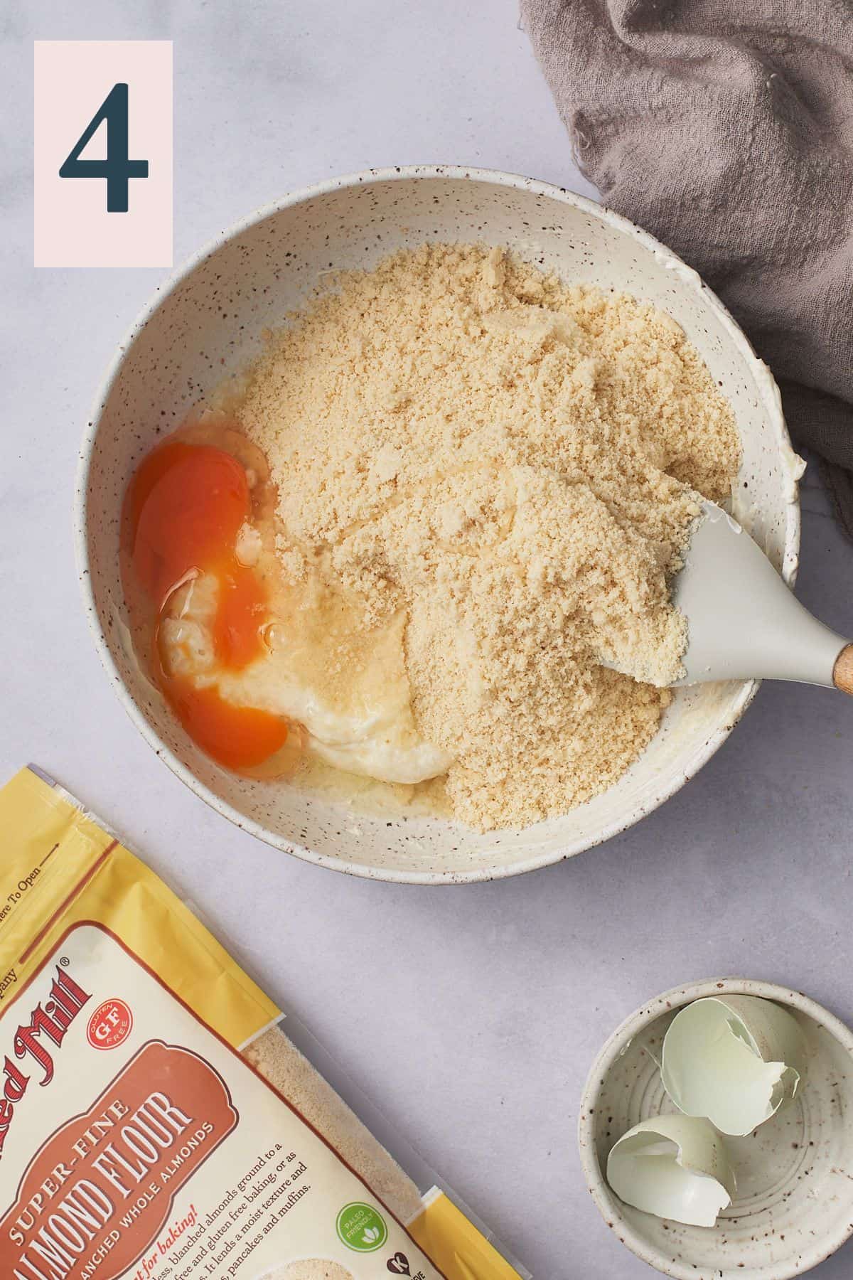 almond flour mixture and egg in a mixing bowl with melted cheese and a rubber spatula and a number 4 in the top left hand corner. 