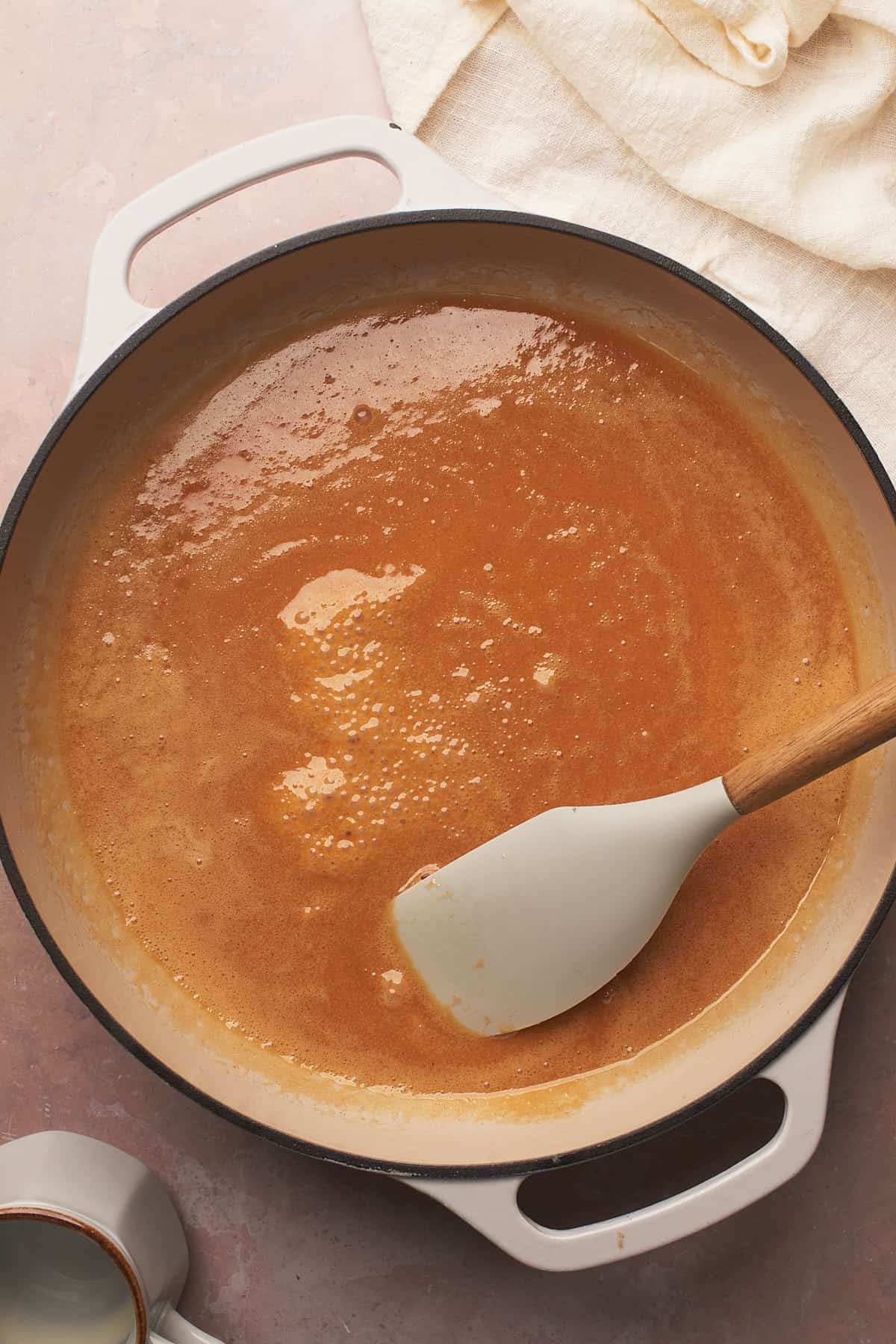 rubber spatula in an enameled skillet with a bubbling caramel mixture. 