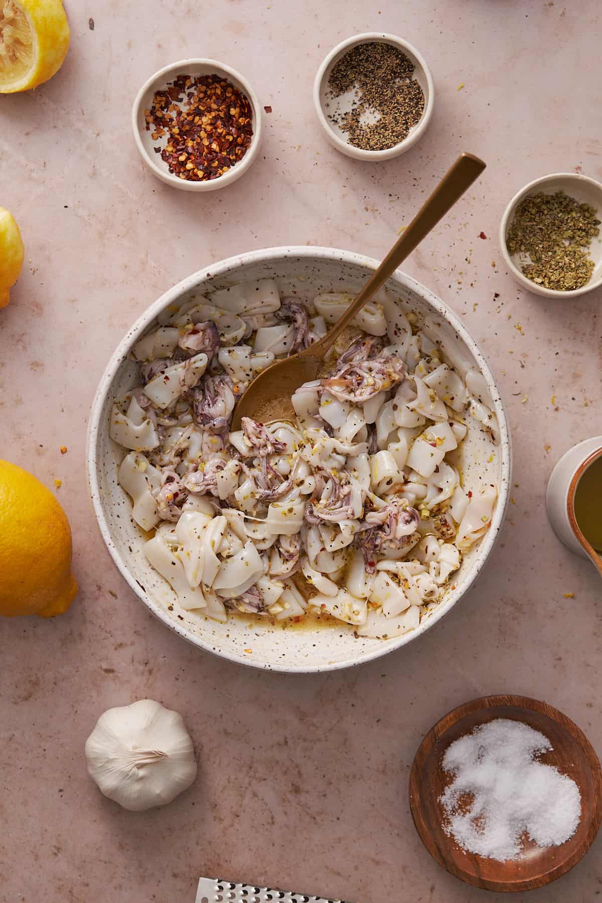 calamari in a bowl marinating with seasonings, olive oil and lemon juice. 