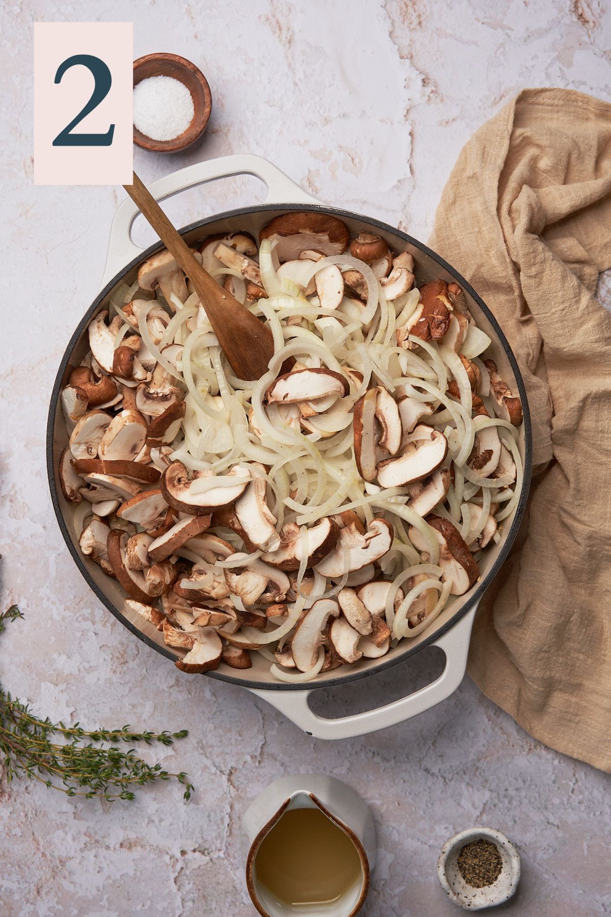 onions and mushrooms in a large skillet with a wooden spoon, and thyme nearby.