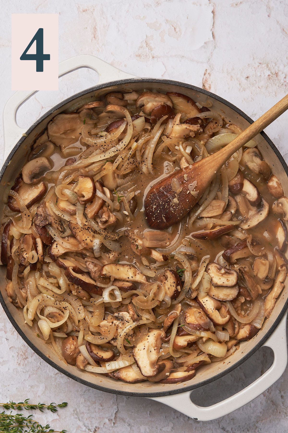 mushrooms and onions in a pan with liquids.