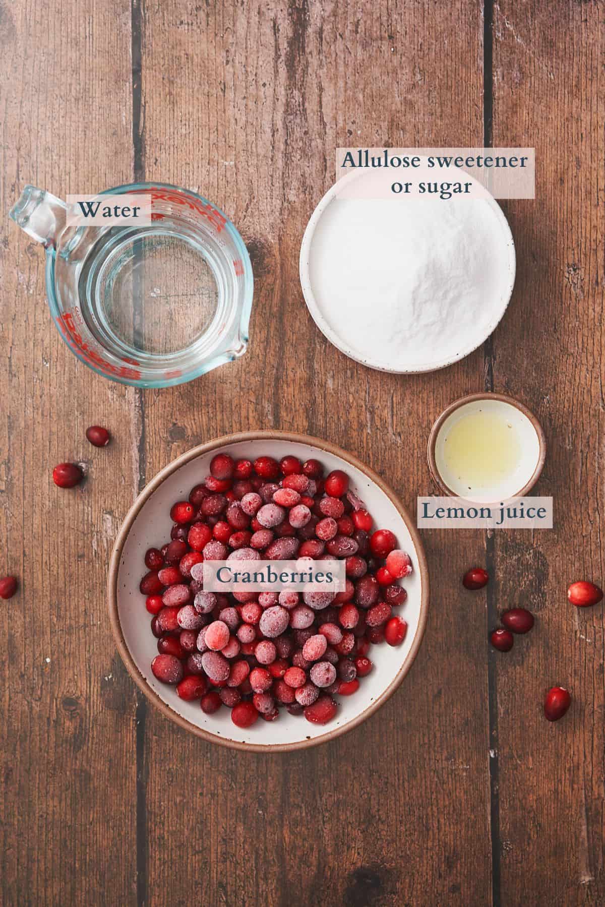 ingredients to make cranberry simple syrup laid out in bowls with text overlaying to denote each ingredient. 