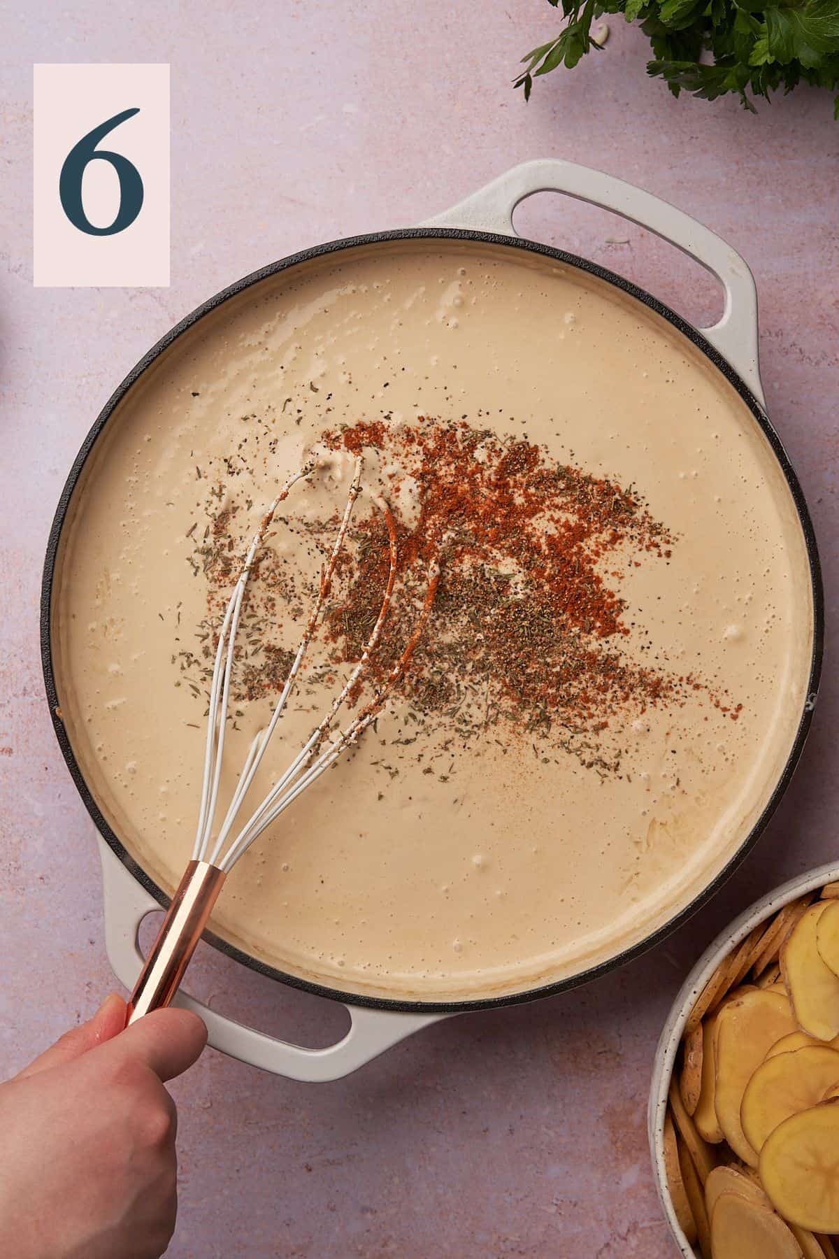 cheese sauce with spices added to the mixture in a skillet with a whisk.