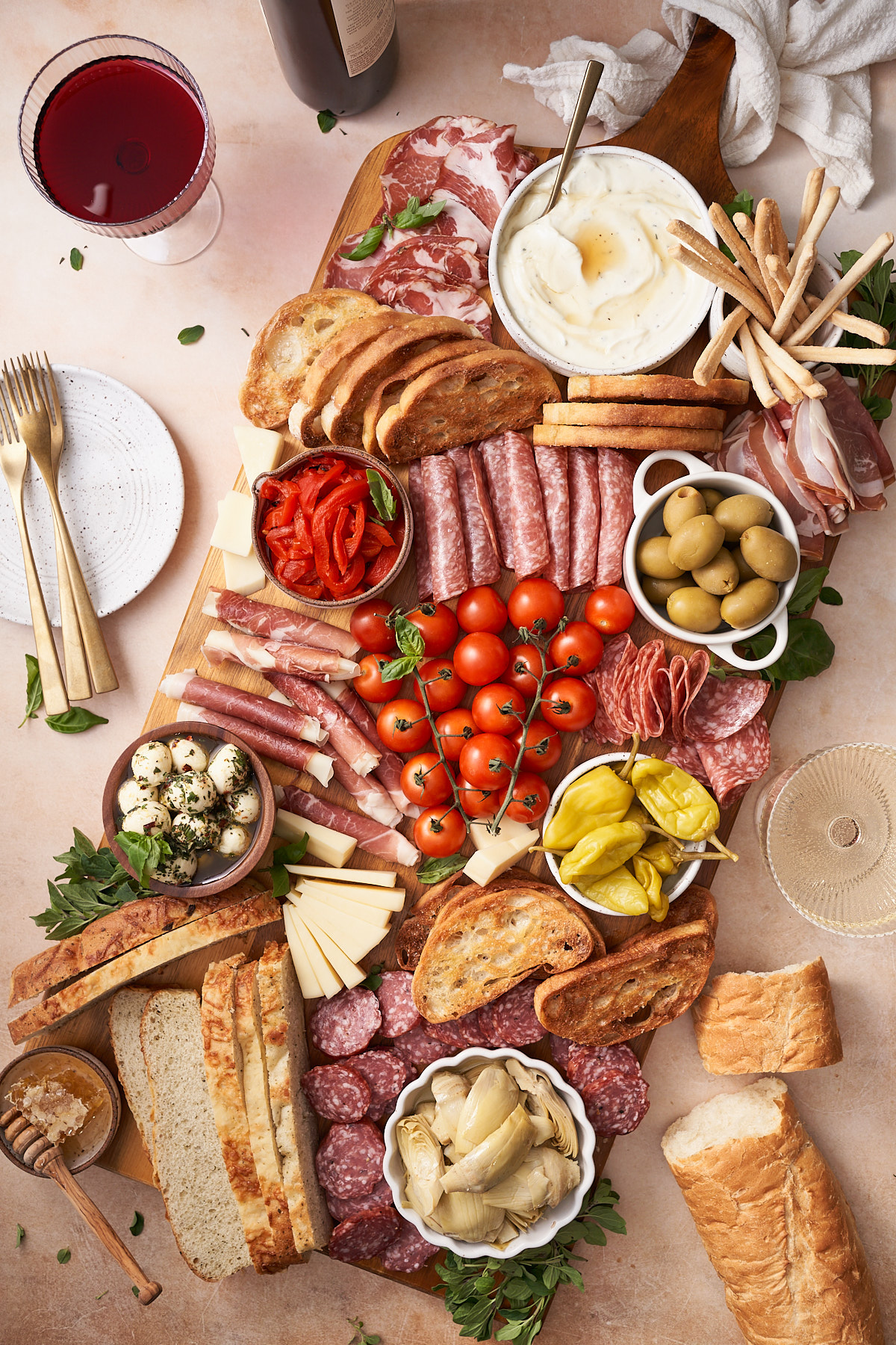 Platter of italian antipasto with lots of meats, cheeses, breads, crackers, olives, peppers and more with both red and white wine. 